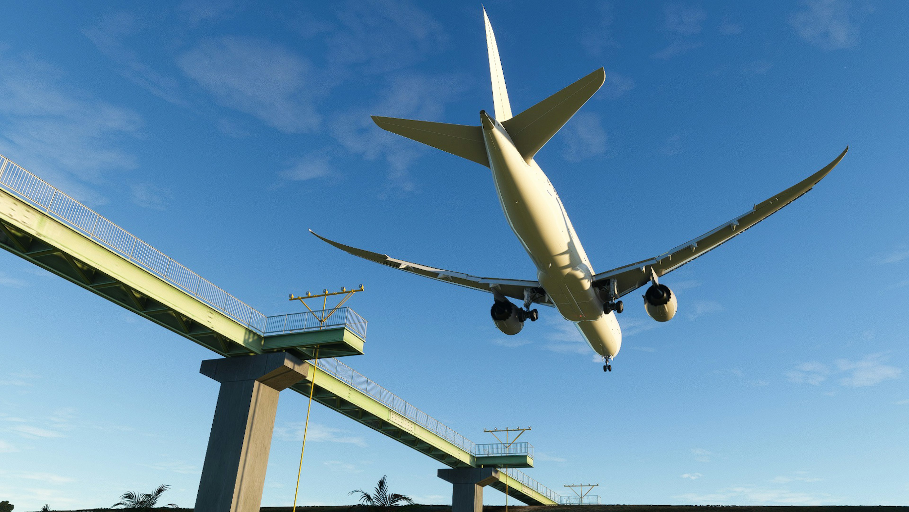 An airplane flying above a bridge structure against a clear blue sky