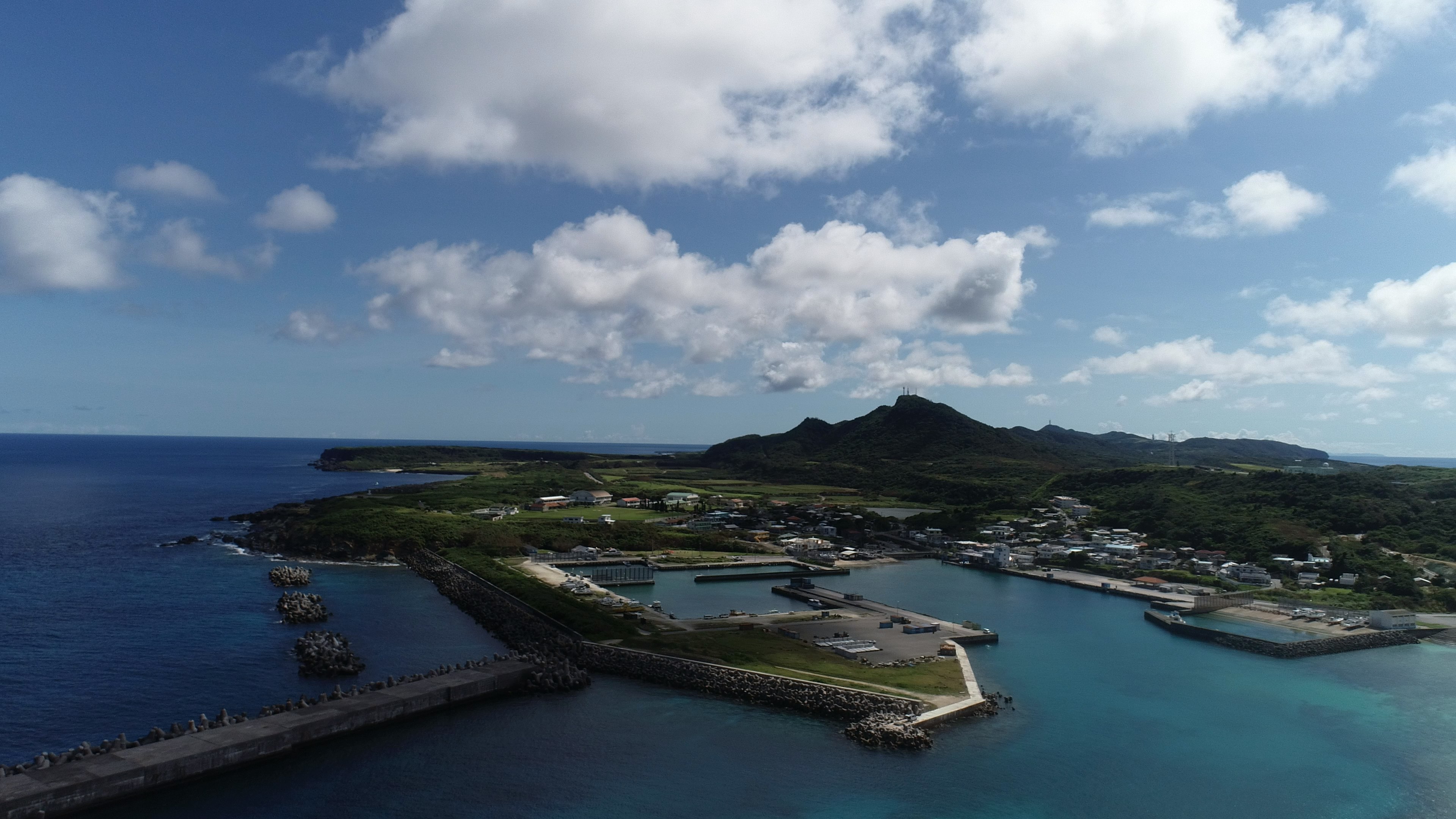 ทิวทัศน์ทางอากาศที่สวยงามของท่าเรือชายฝั่งล้อมรอบด้วยน้ำสีฟ้าและเนินเขาสีเขียว