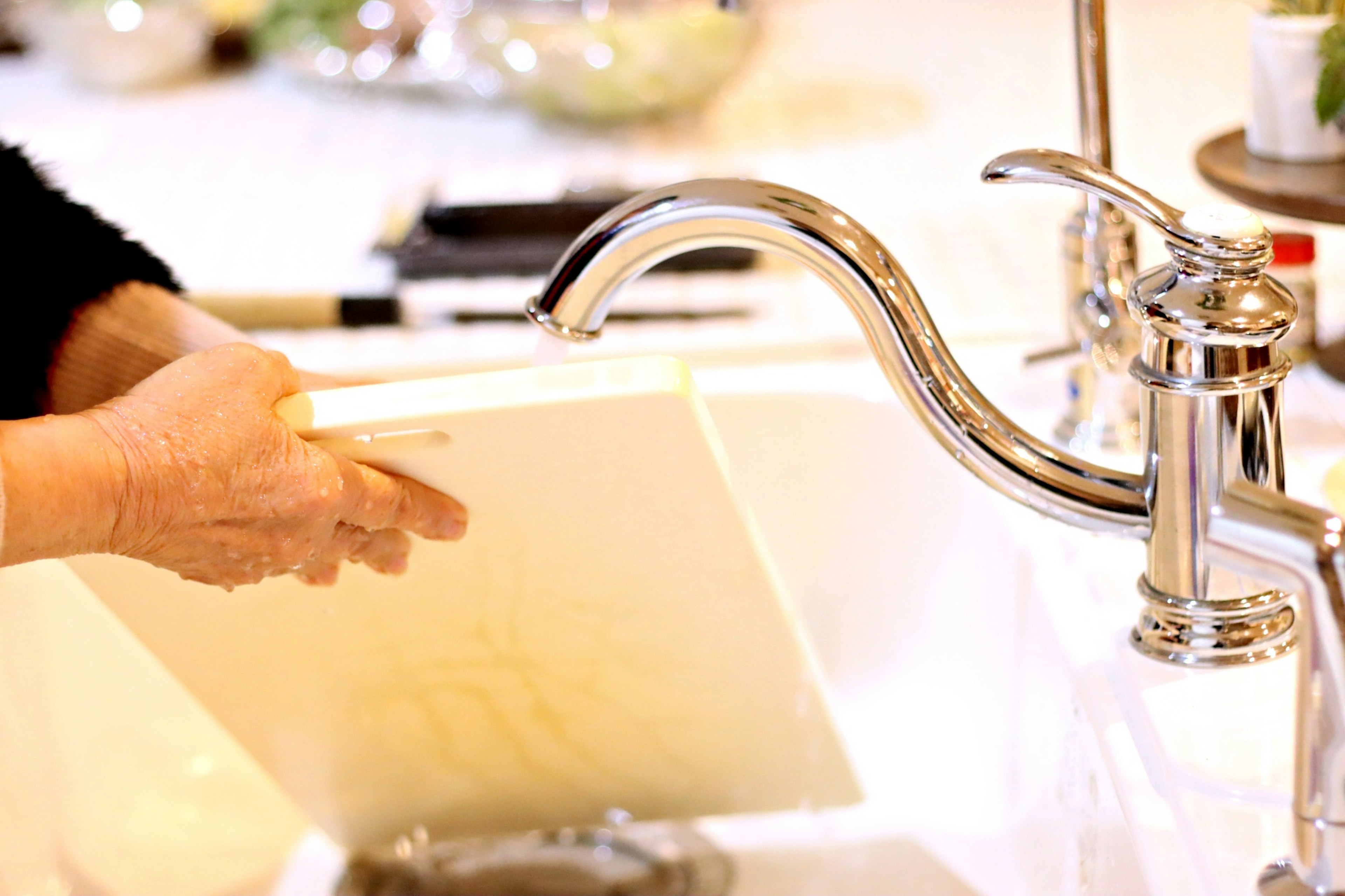 Hands washing kitchen utensils in a sink