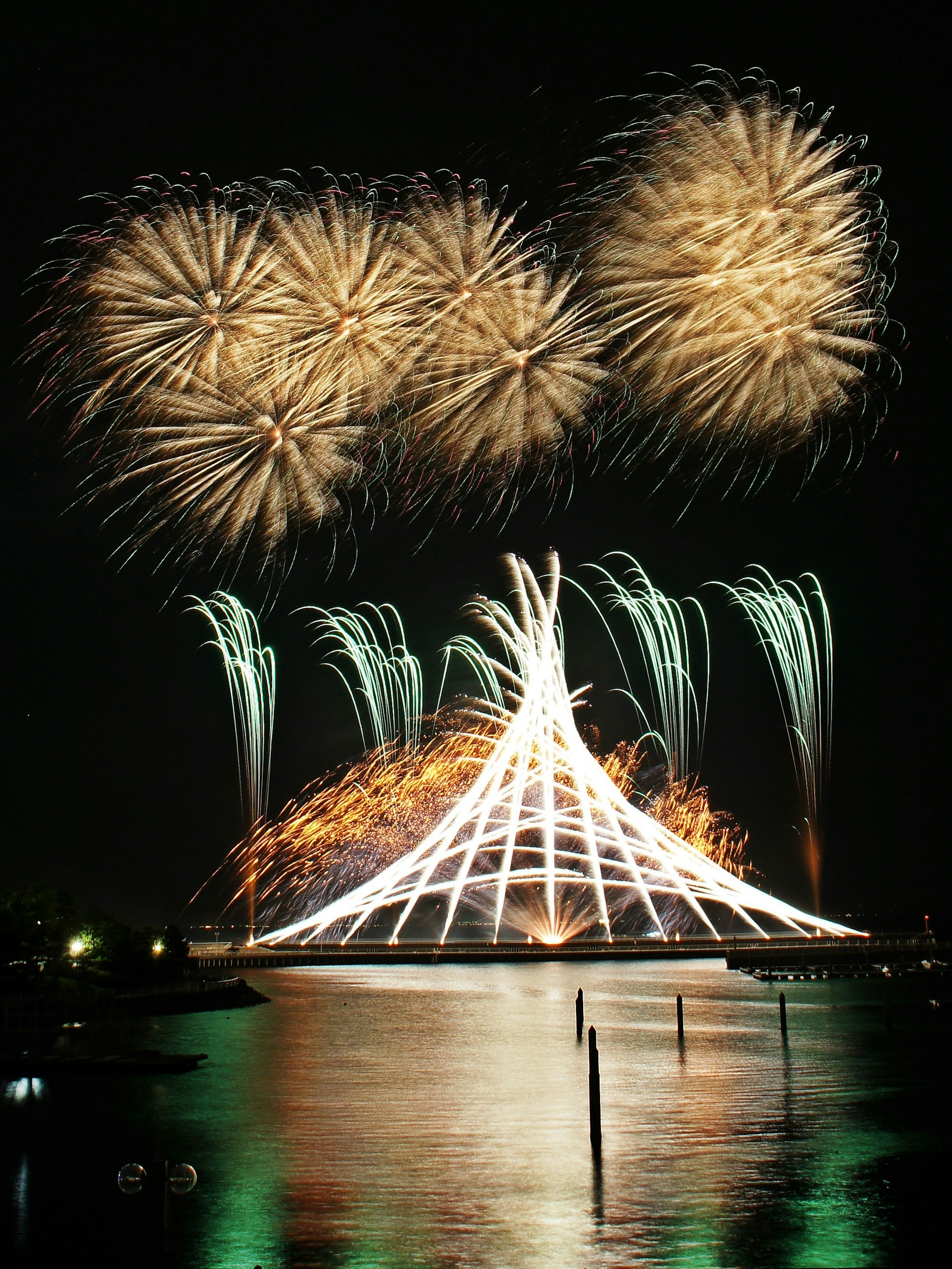 Impresionante espectáculo de fuegos artificiales sobre el agua con reflejos nocturnos