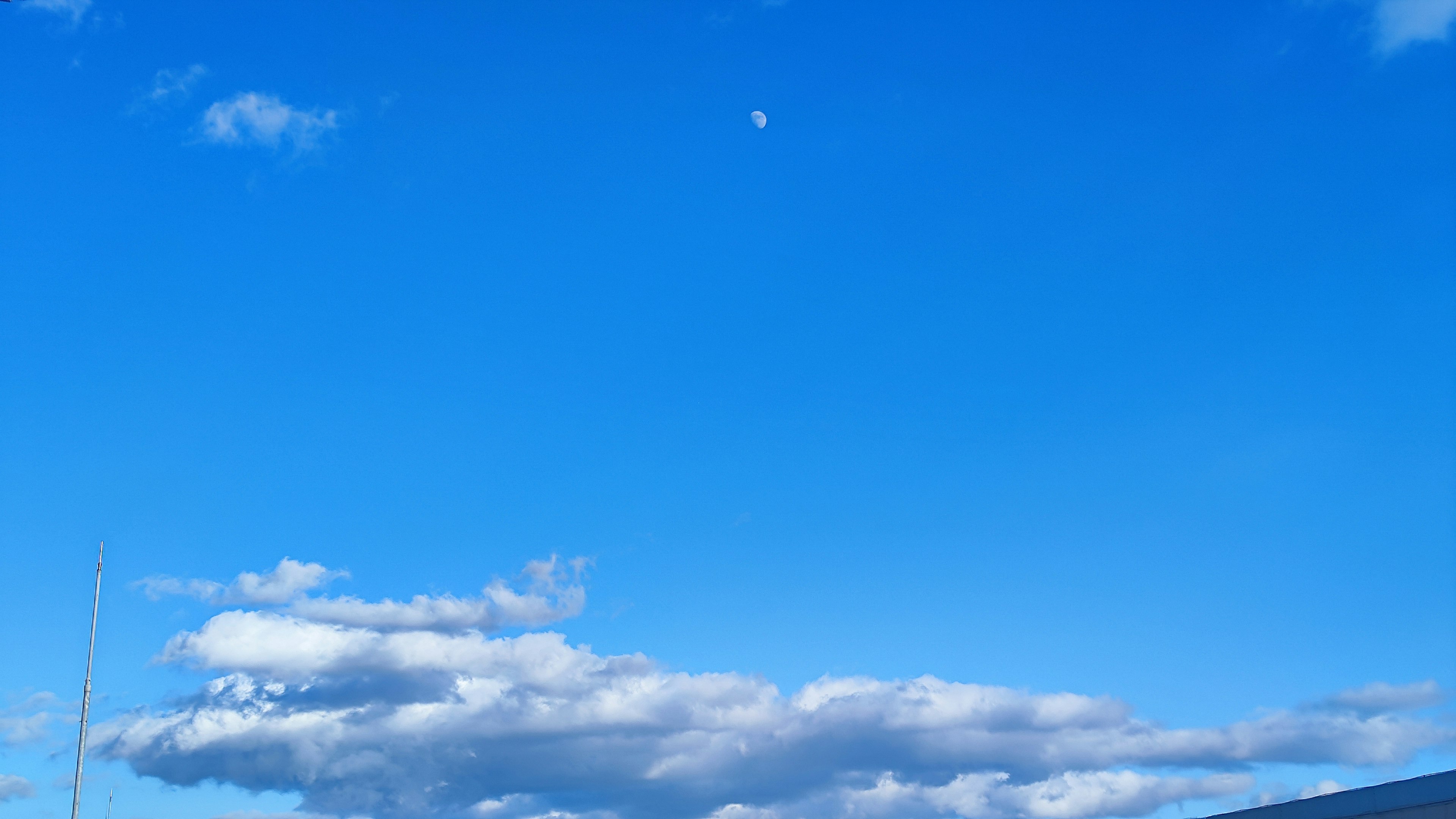 Langit biru dengan awan putih dan bulan yang terlihat