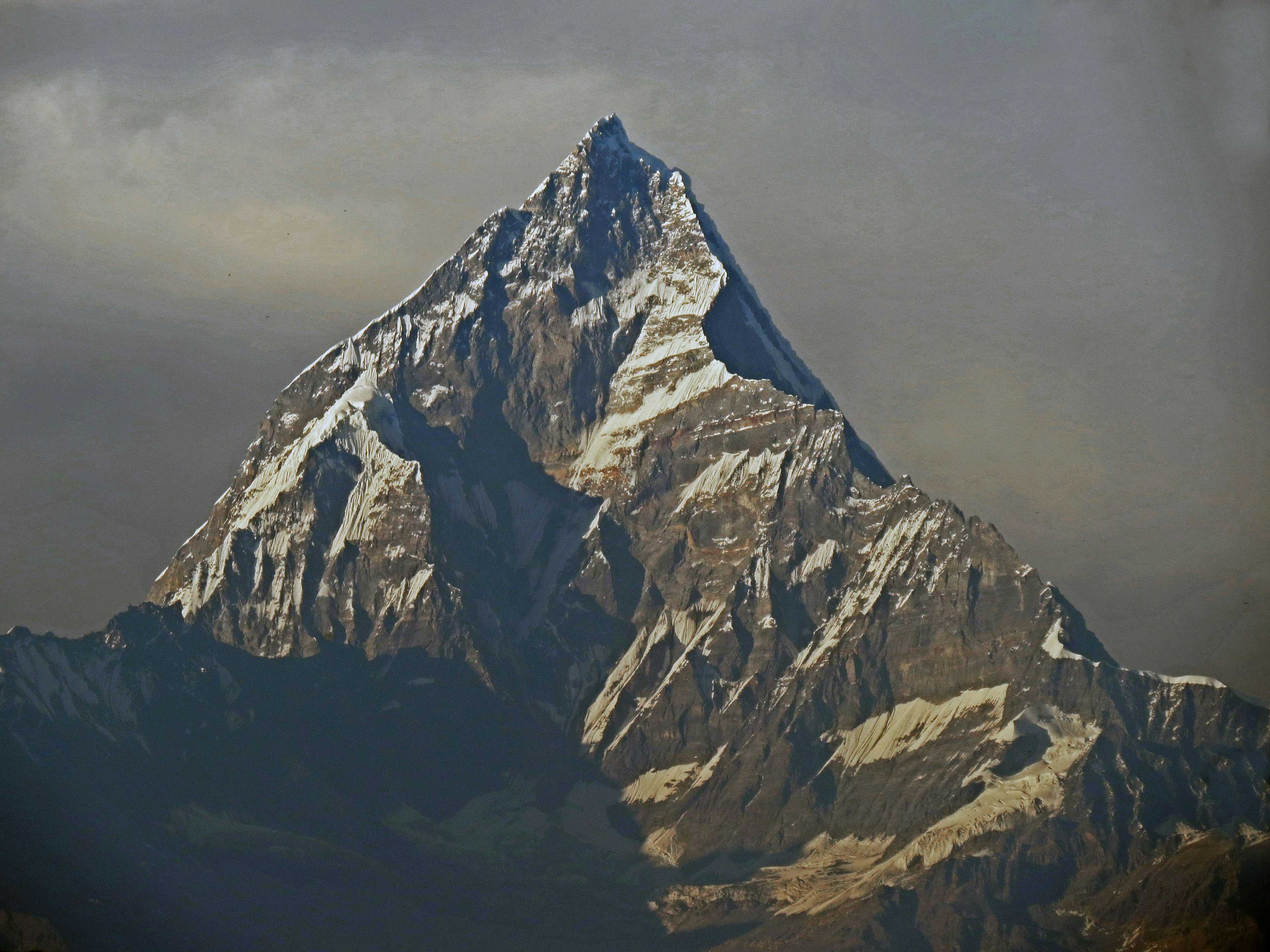 Schneebedeckter majestätischer Berggipfel, der sich gegen einen bewölkten Himmel erhebt