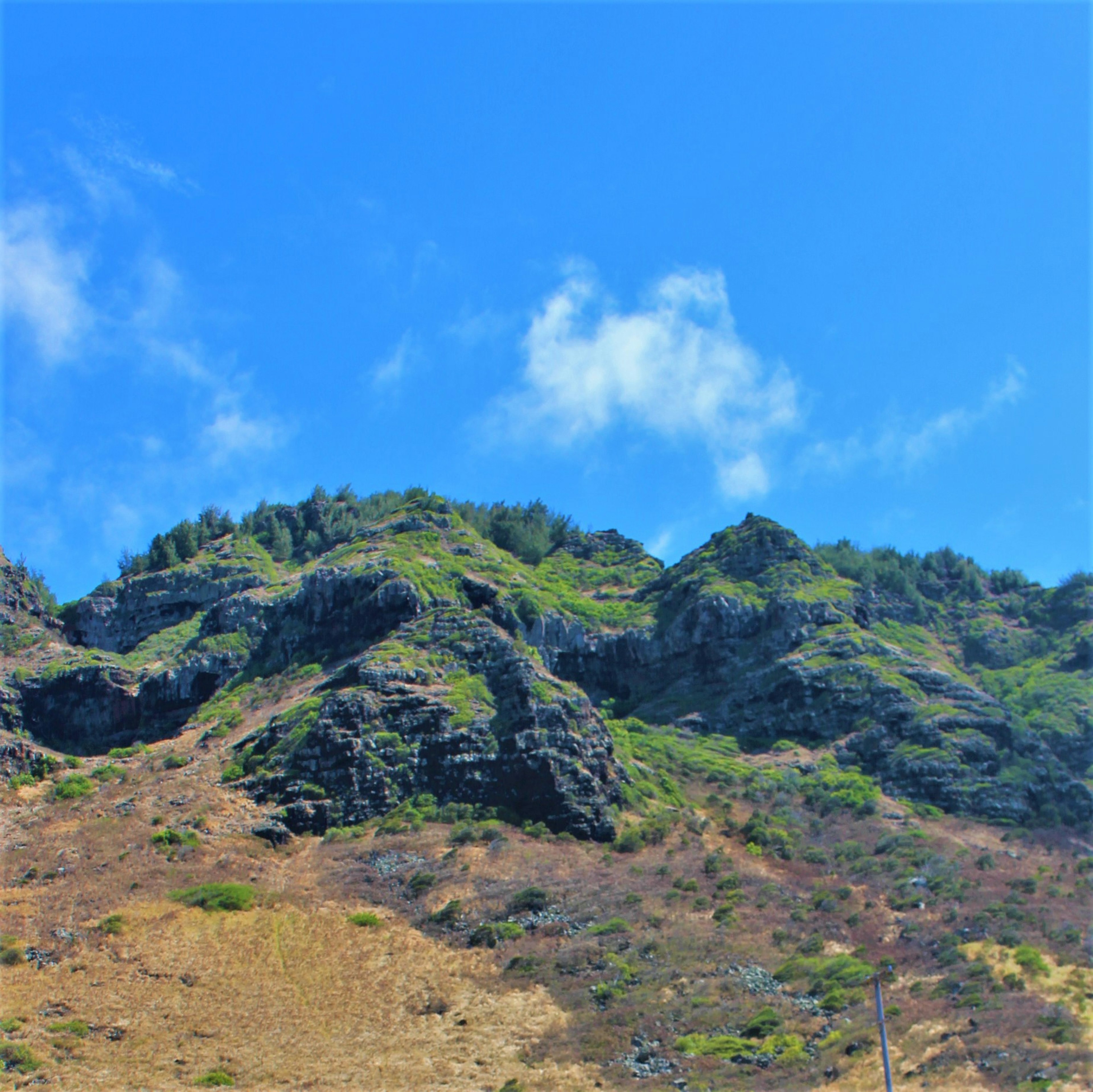 Landschaft mit grünen Bergen und Felsen unter blauem Himmel