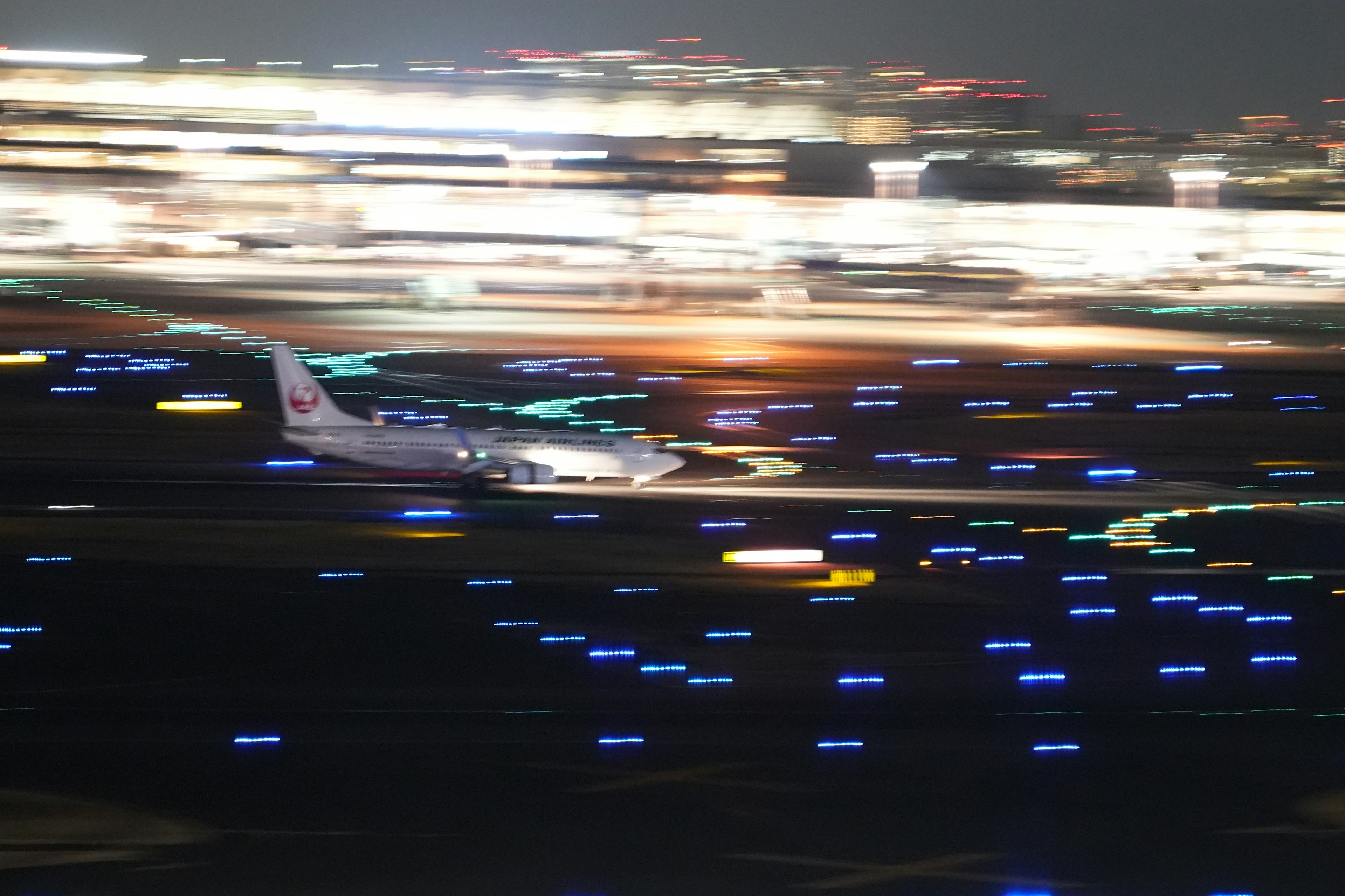 夜の空港で滑走路を滑走する飛行機の写真