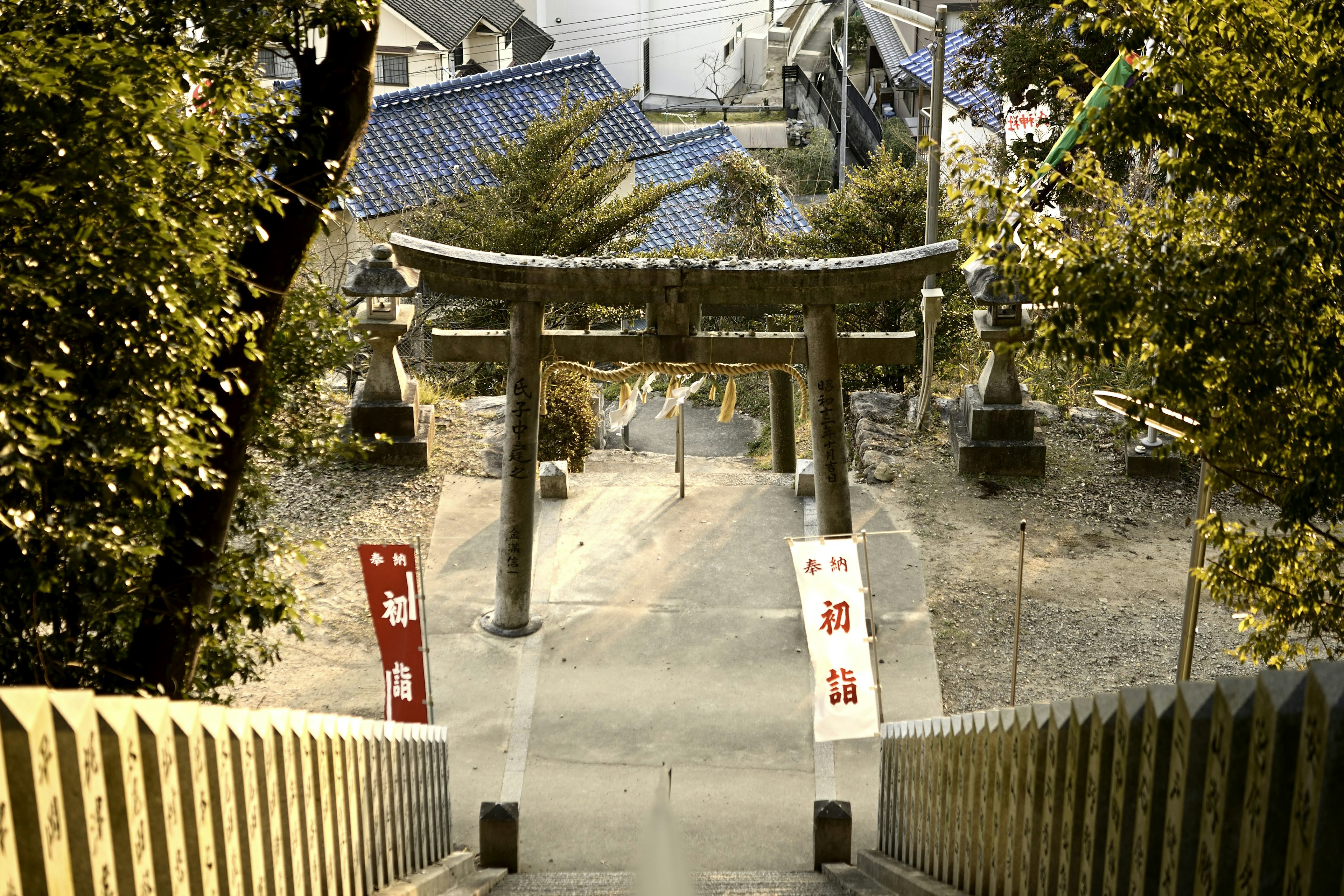 Vue d'un torii et d'escaliers entourés de verdure et de bannières rouges