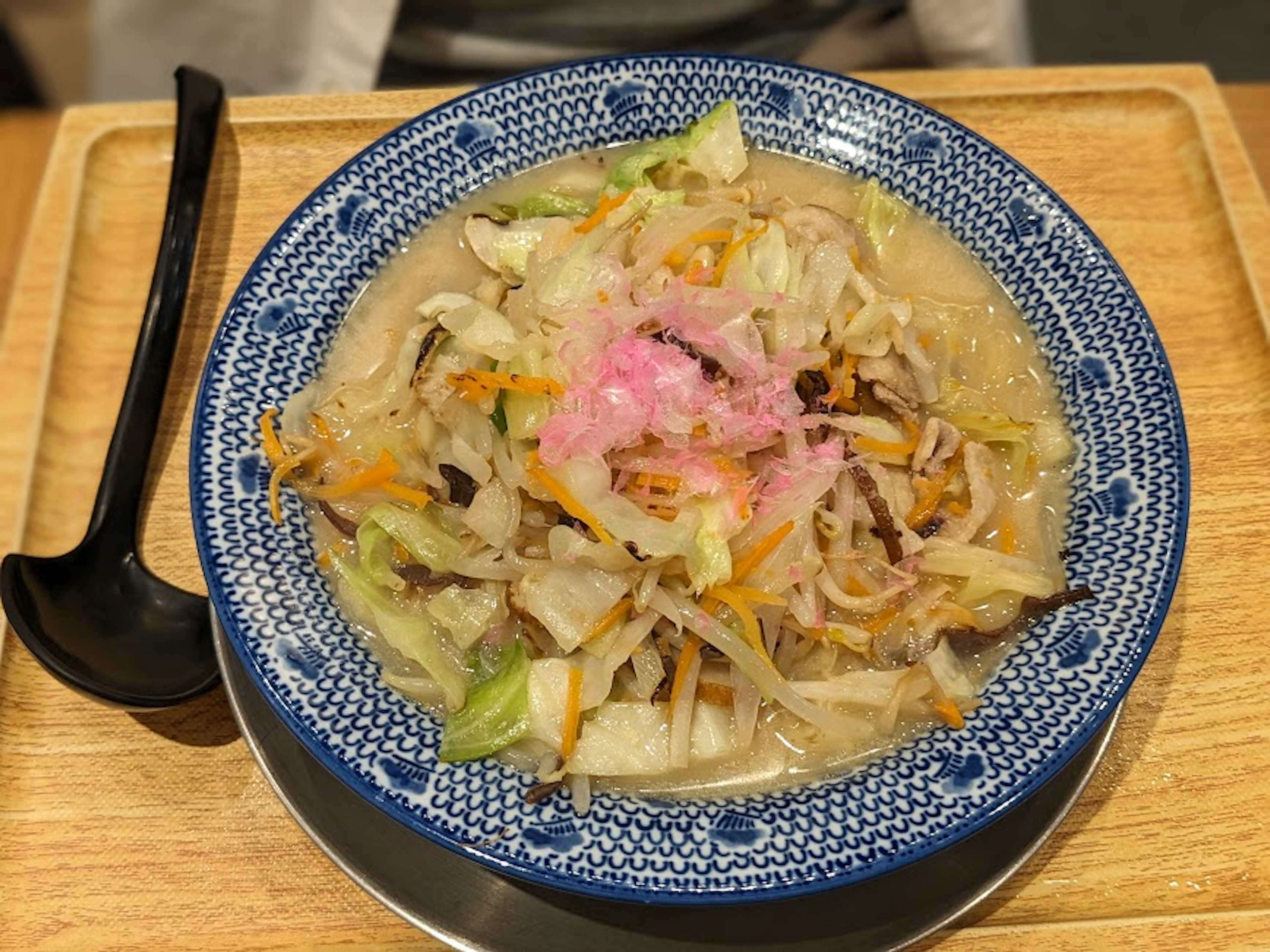 Warm dish featuring colorful vegetables and meat served in a blue bowl