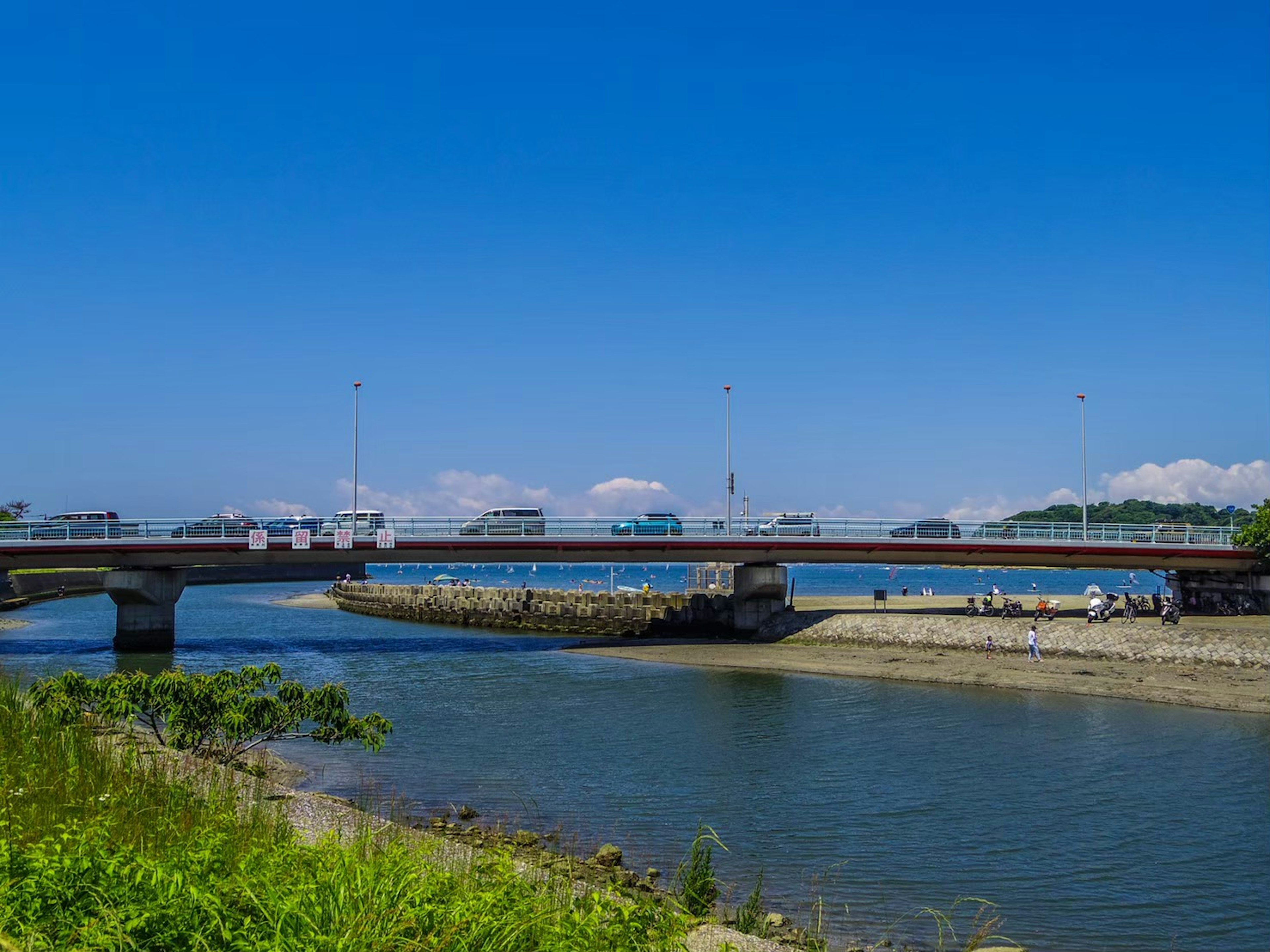 Jembatan di atas sungai tenang di bawah langit biru yang cerah