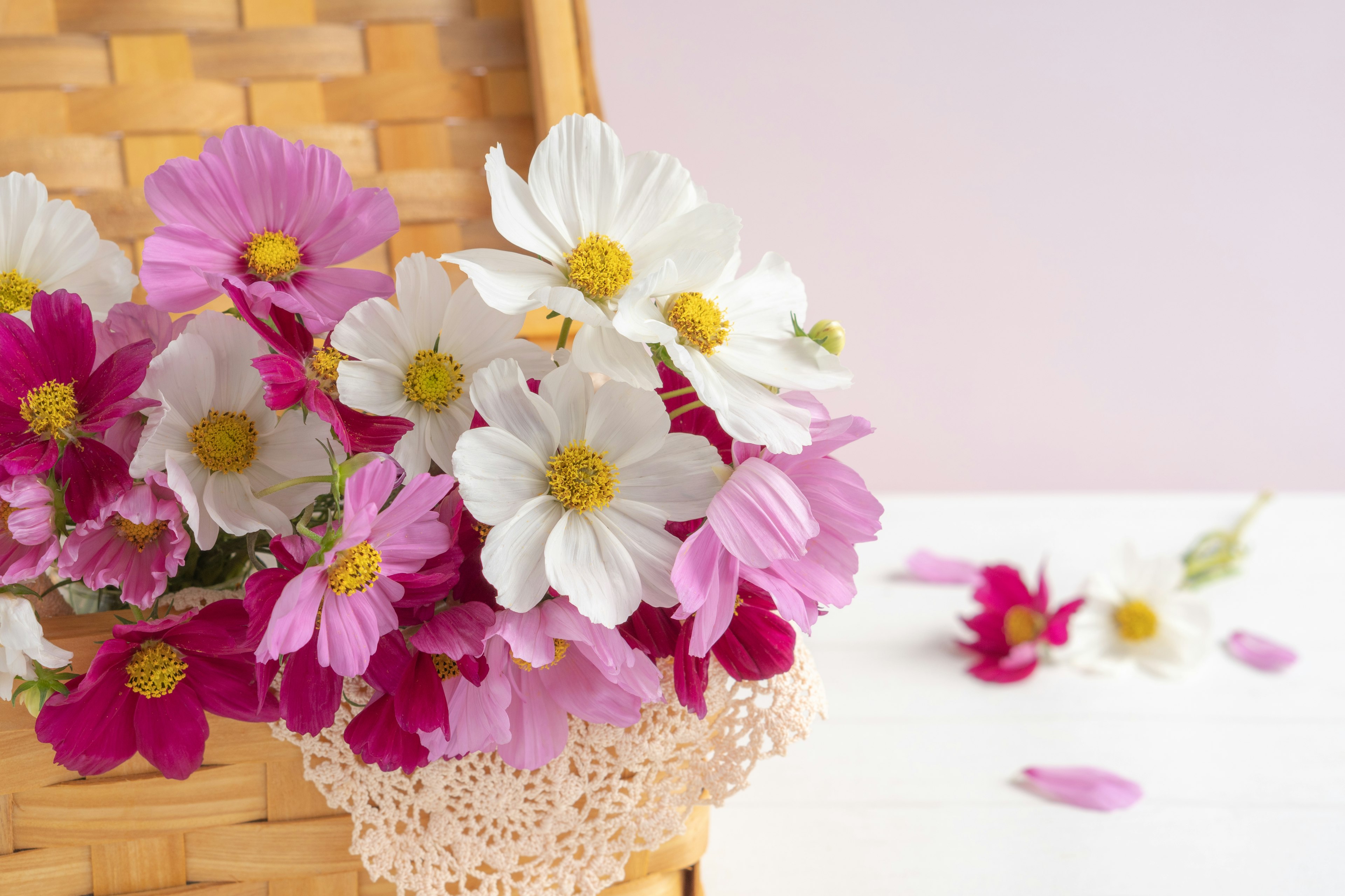 Arrangement magnifique de fleurs blanches et roses dans un panier avec des pétales