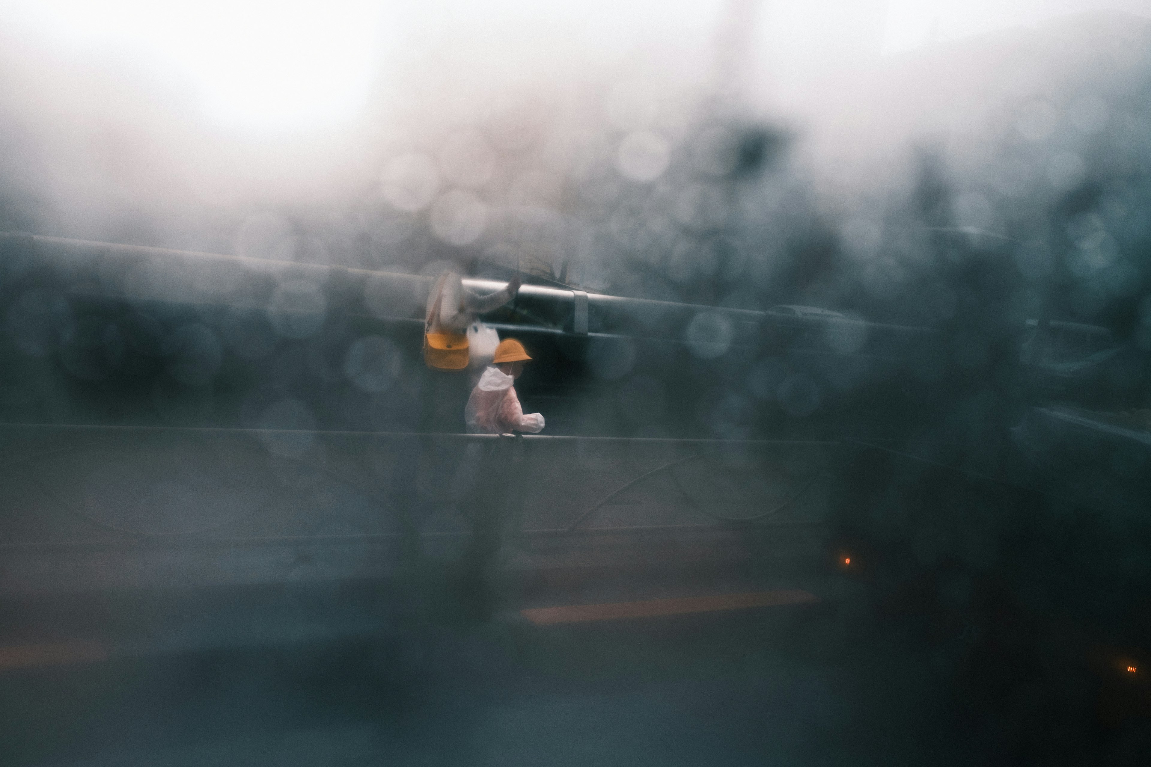 Photo of a worker seen through a rain-soaked window with a blurred background