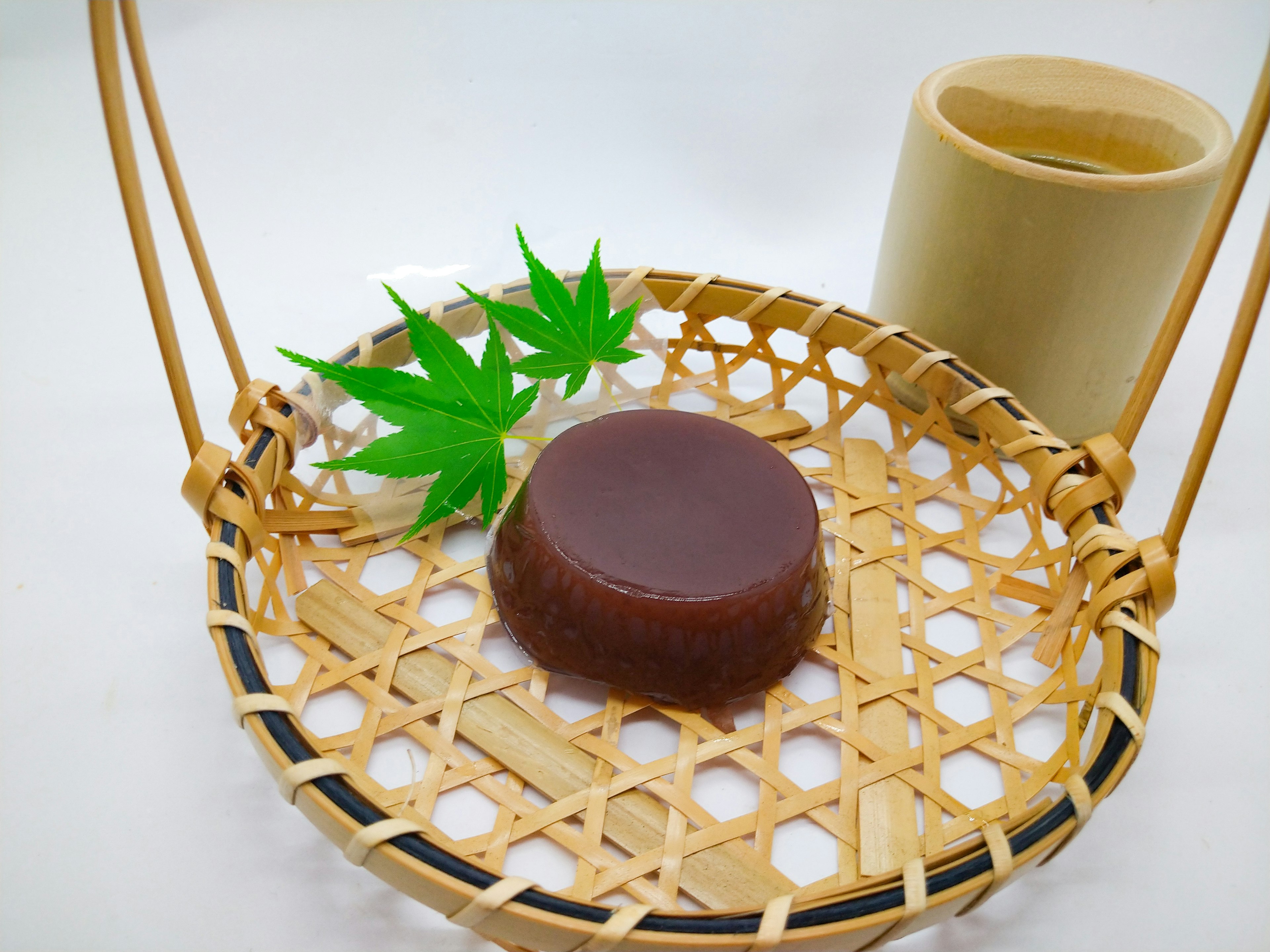 Kue Jepang di keranjang bambu dengan dekorasi daun hijau