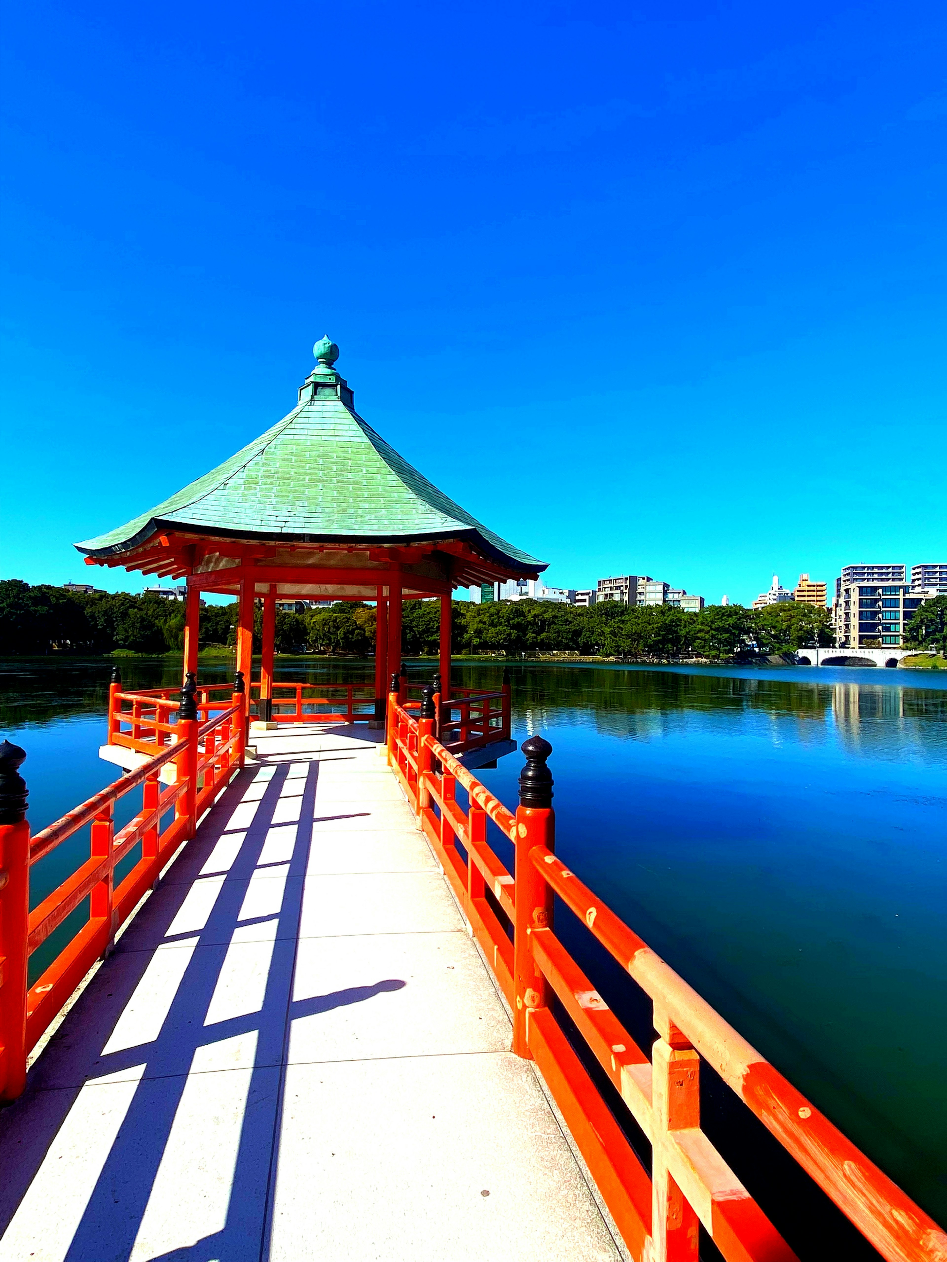 赤い橋と屋根のあるパビリオンが湖に浮かぶ美しい景色