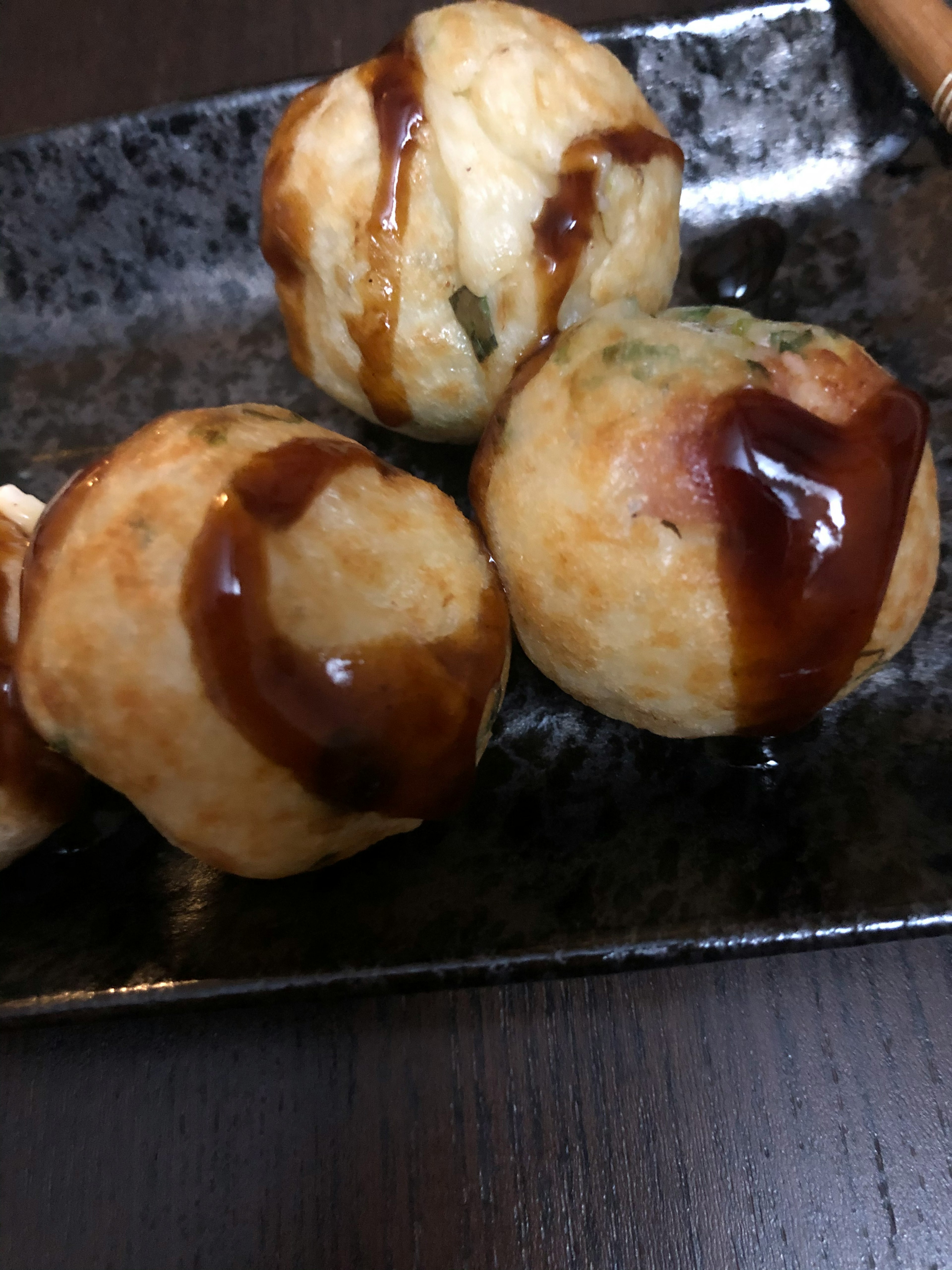 たこ焼きの球状の料理が黒い皿に盛られています