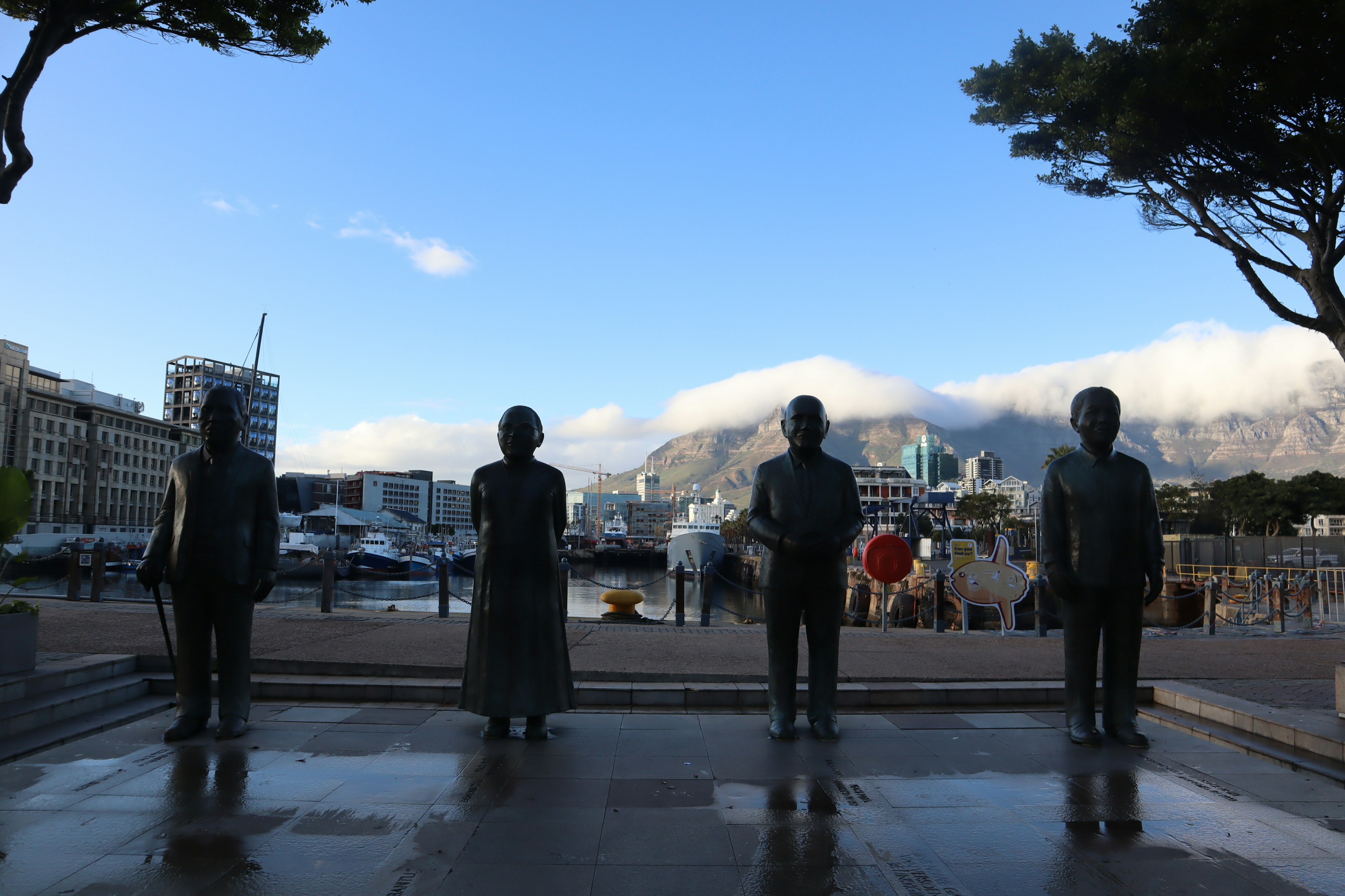 Quattro statue di bronzo in piedi sul lungomare di Cape Town con uno sfondo panoramico