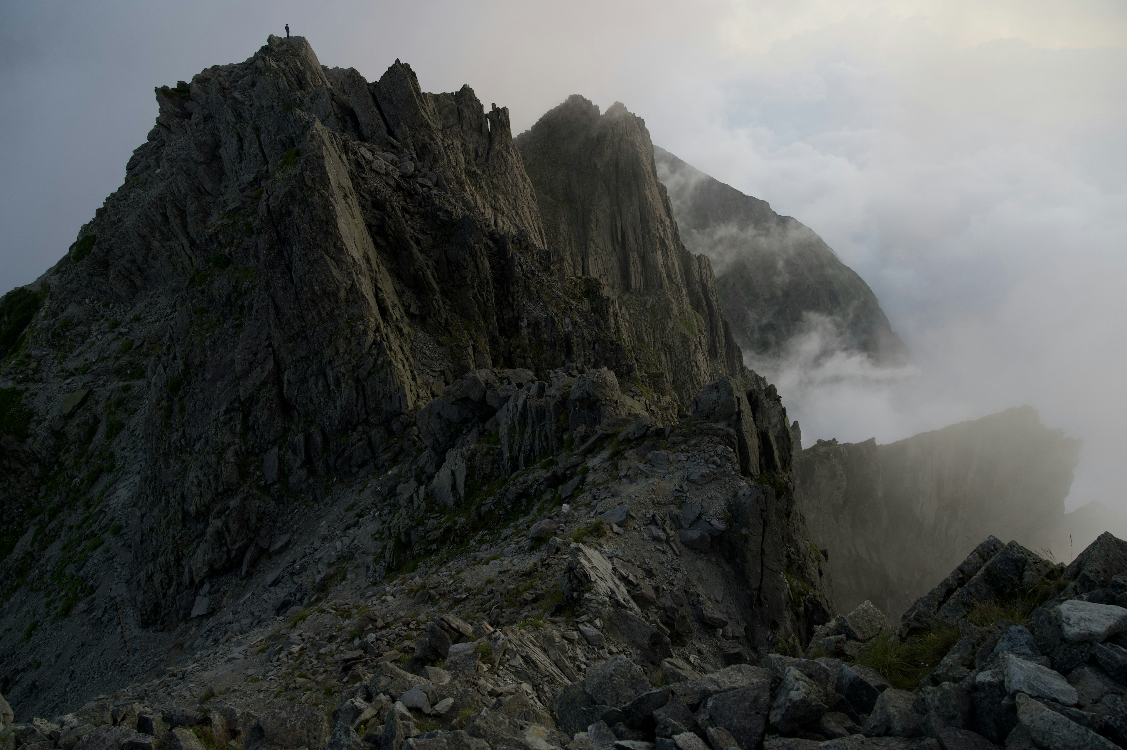 A rugged mountain peak shrouded in clouds with rocky terrain