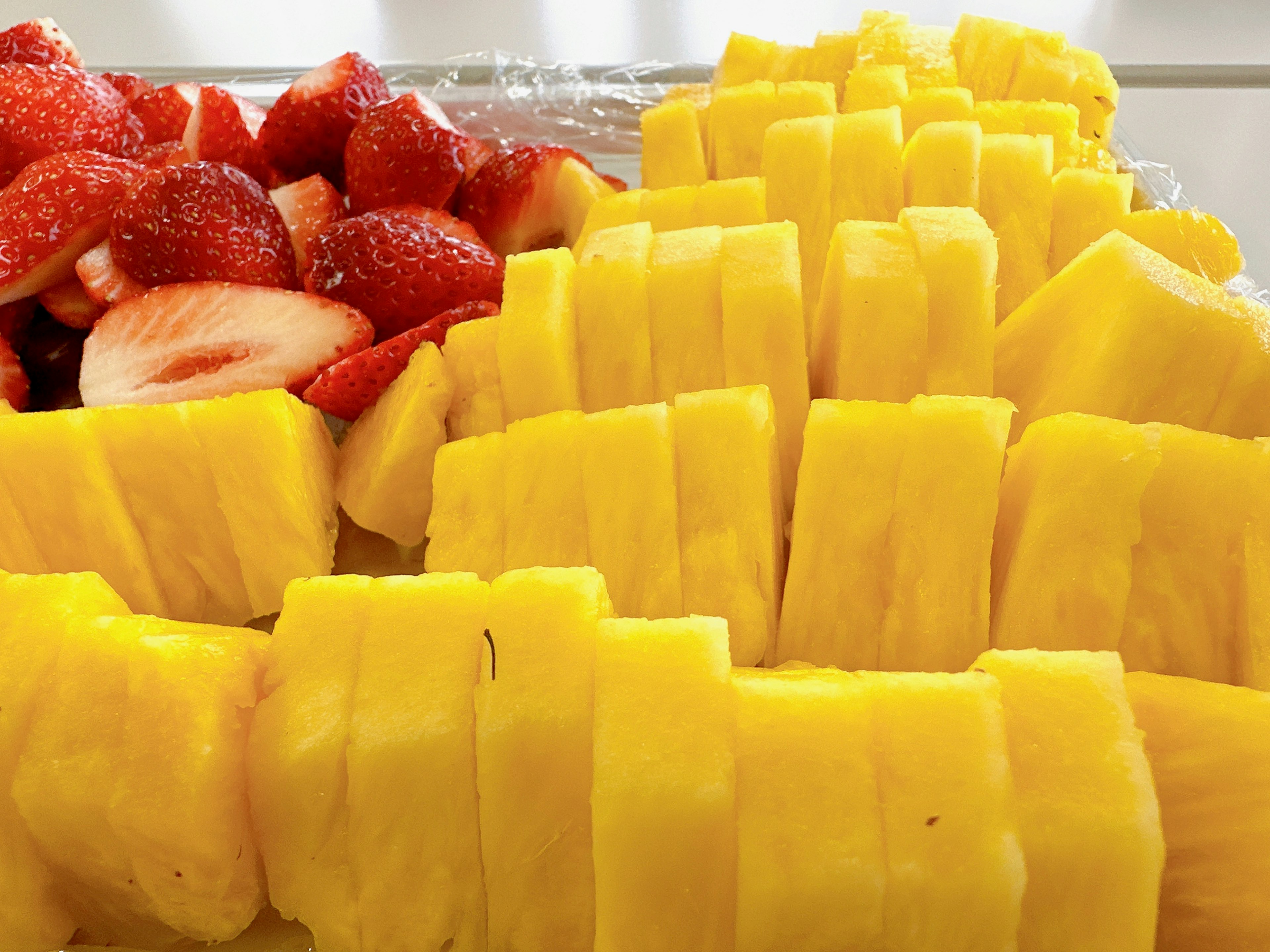 Piña fresca y fresas dispuestas en una bandeja piña cortada en piezas uniformes