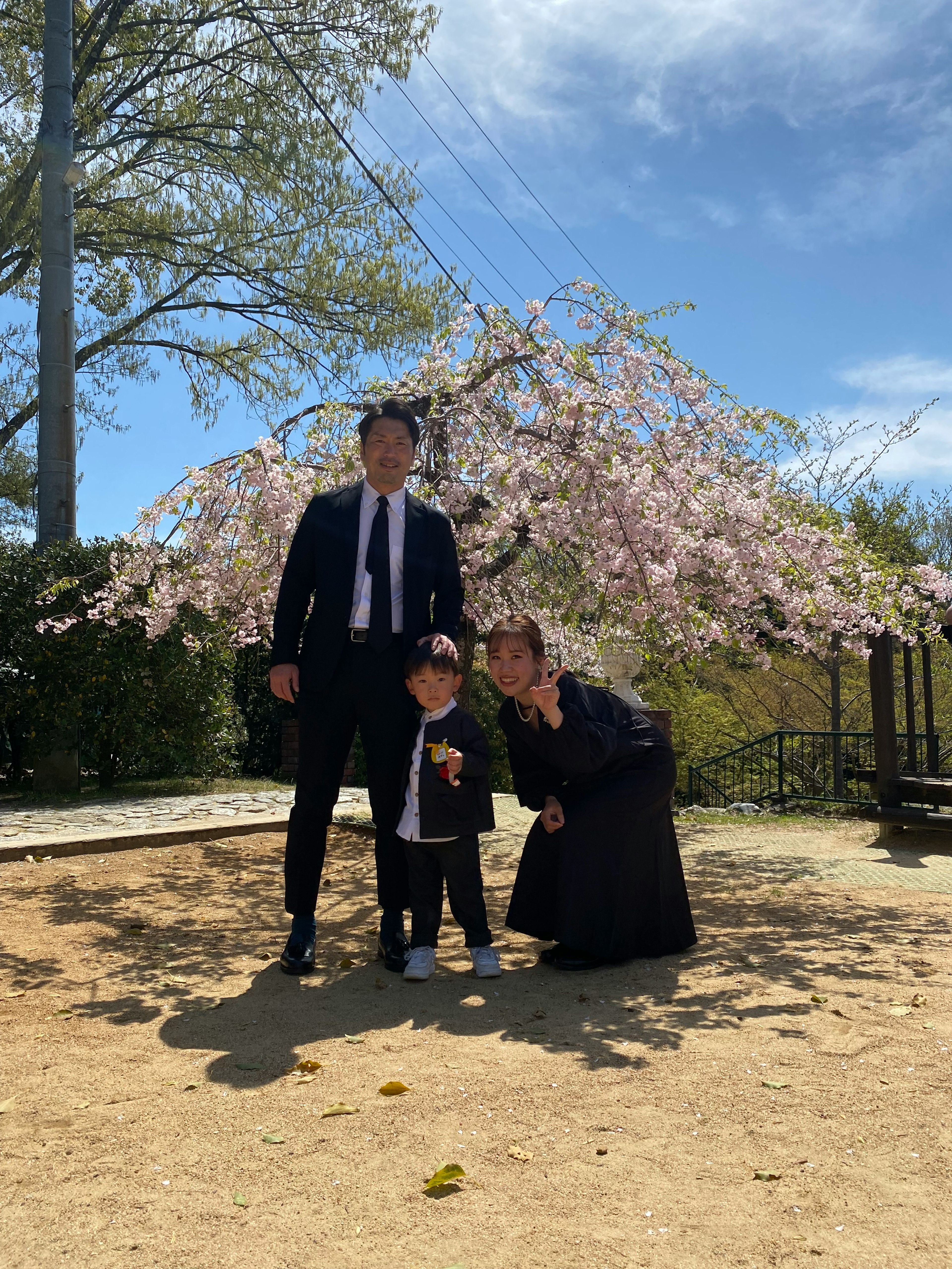 Foto keluarga di bawah pohon sakura dengan orang tua dan anak tersenyum