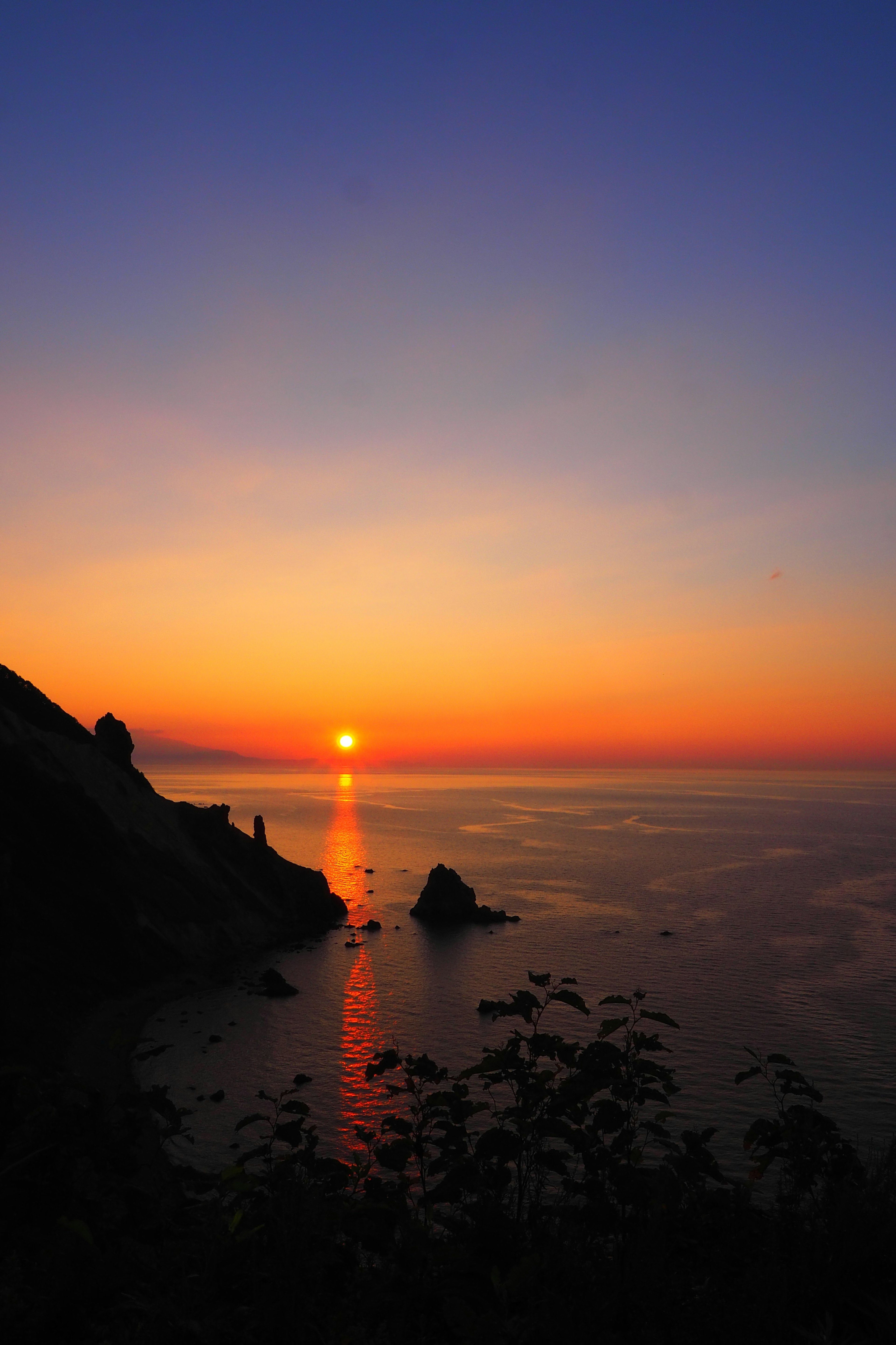 海に沈む夕日と色とりどりの空