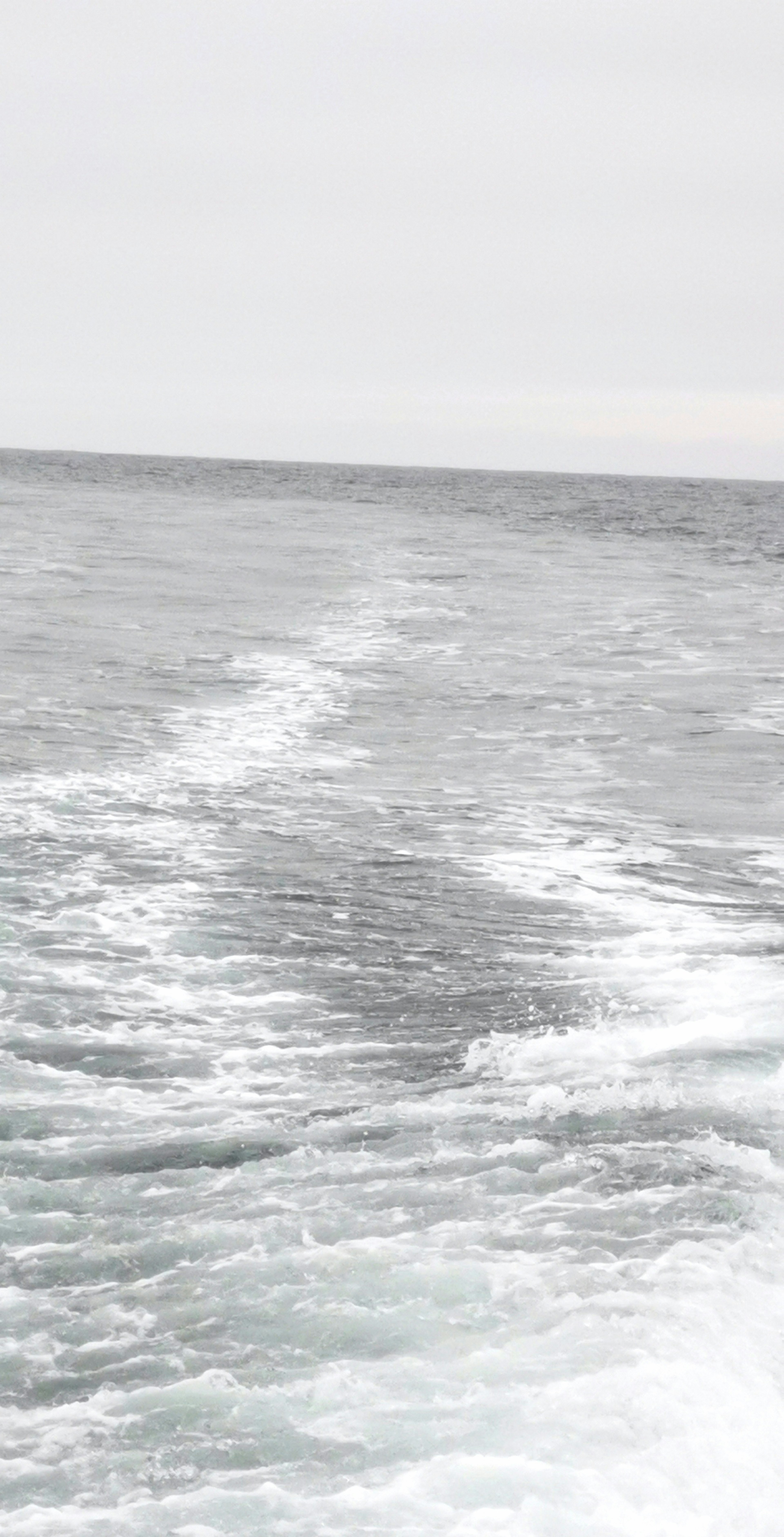 Vue sur une mer calme avec des traces de sillage blanches