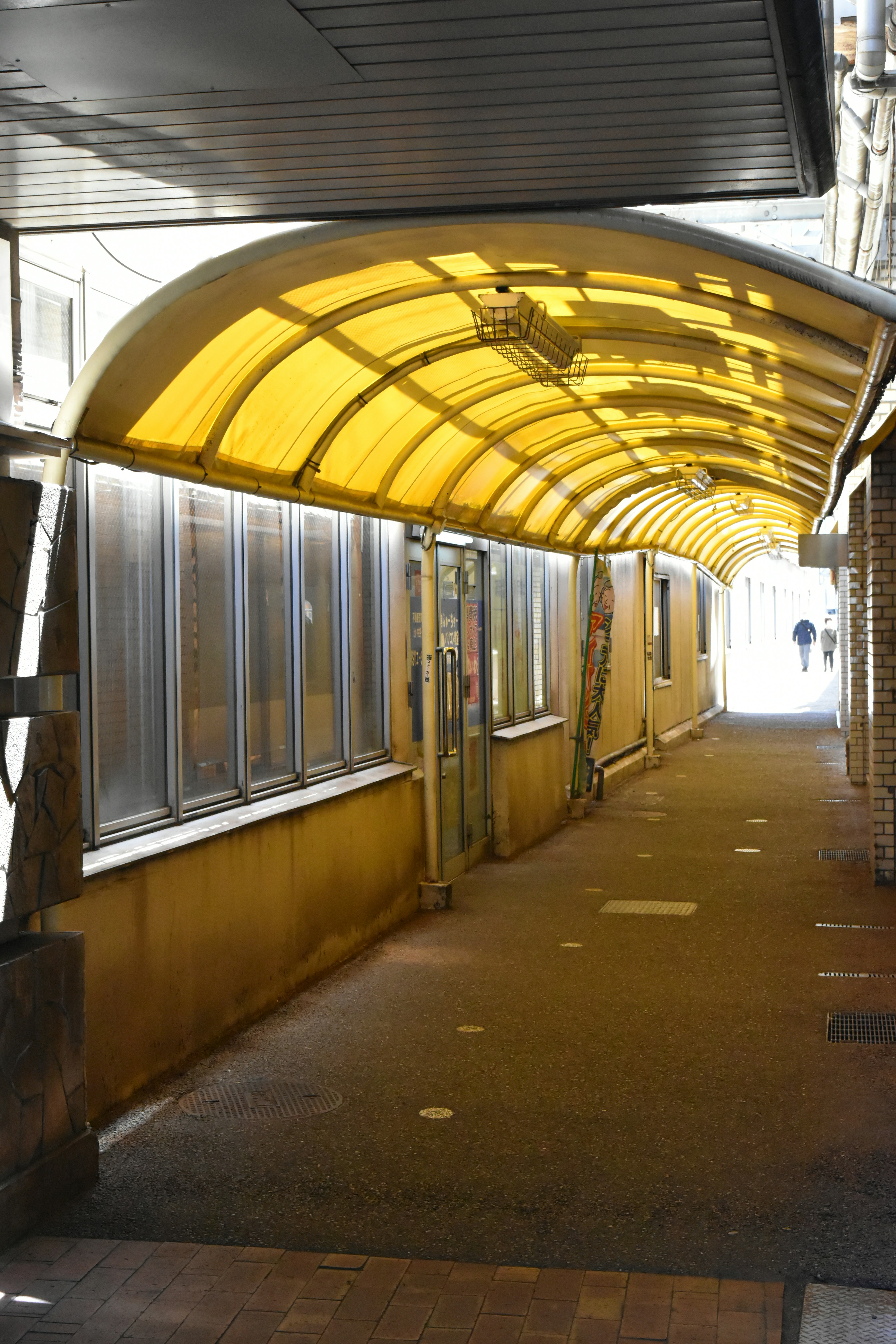 Innensicht eines Durchgangs mit gelbem Dach und Fenstern entlang der Wand bei hellem Licht