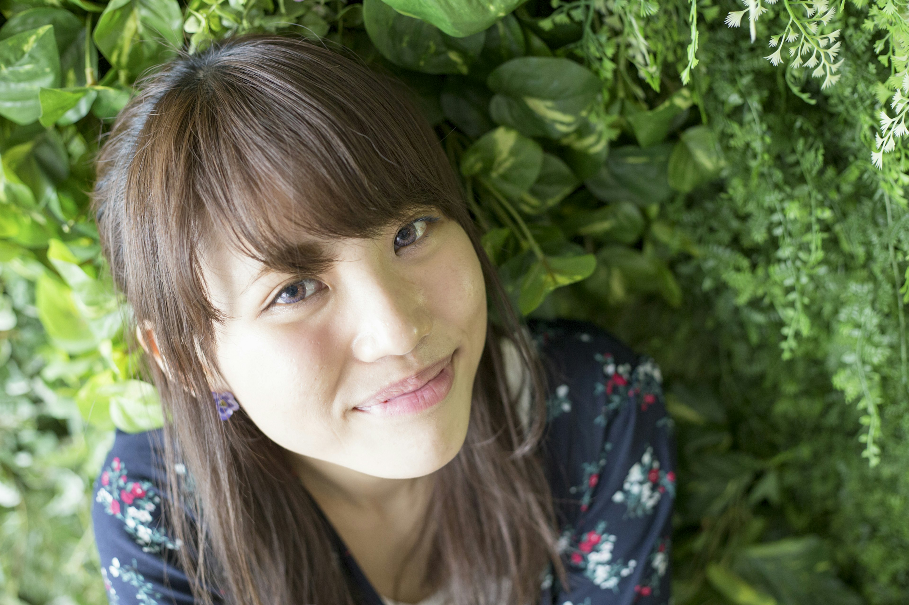 Retrato de una mujer sonriendo frente a un fondo de plantas verdes