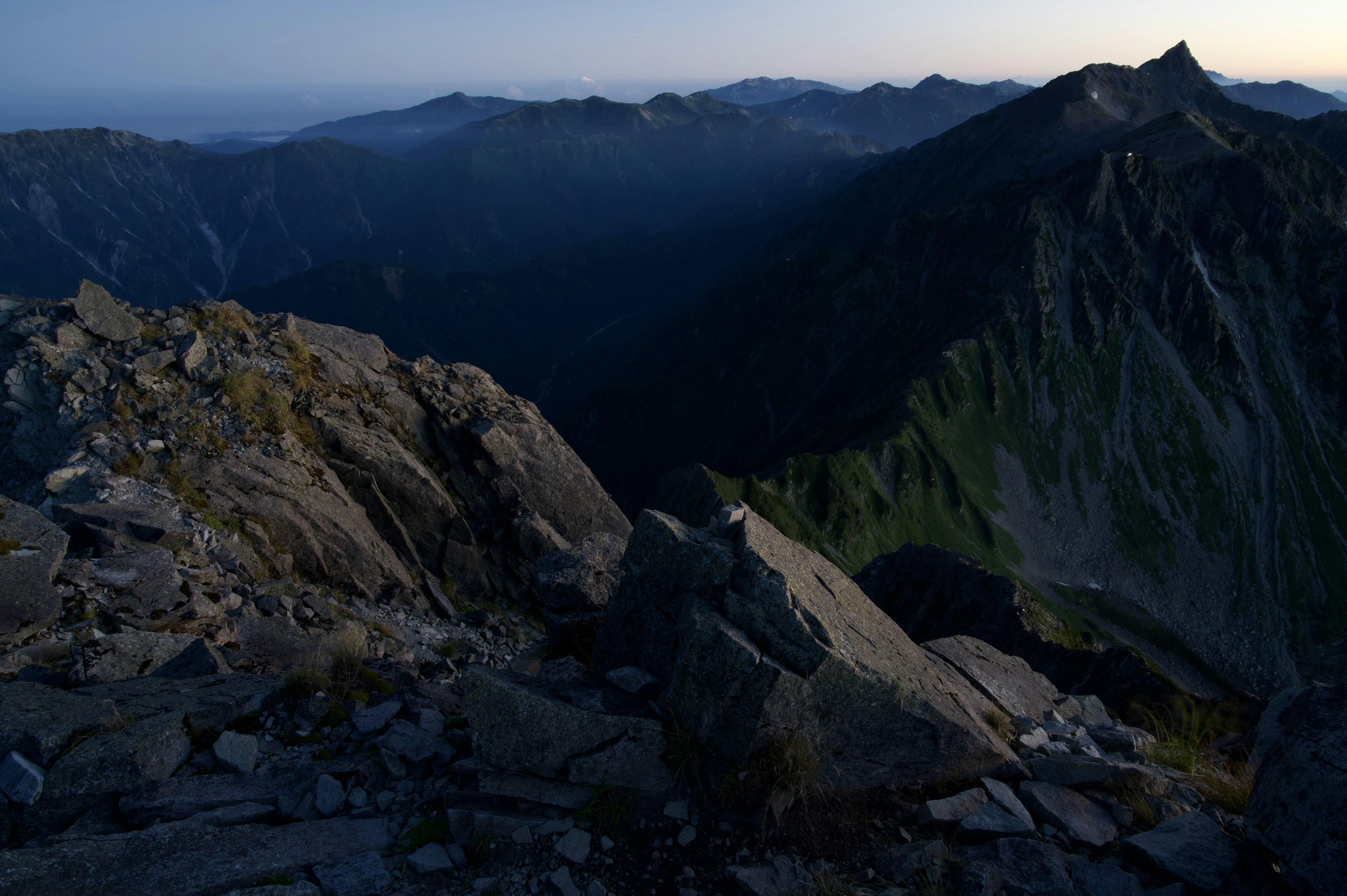 Imagen de una cima de montaña oscura con una vista impresionante de las montañas circundantes