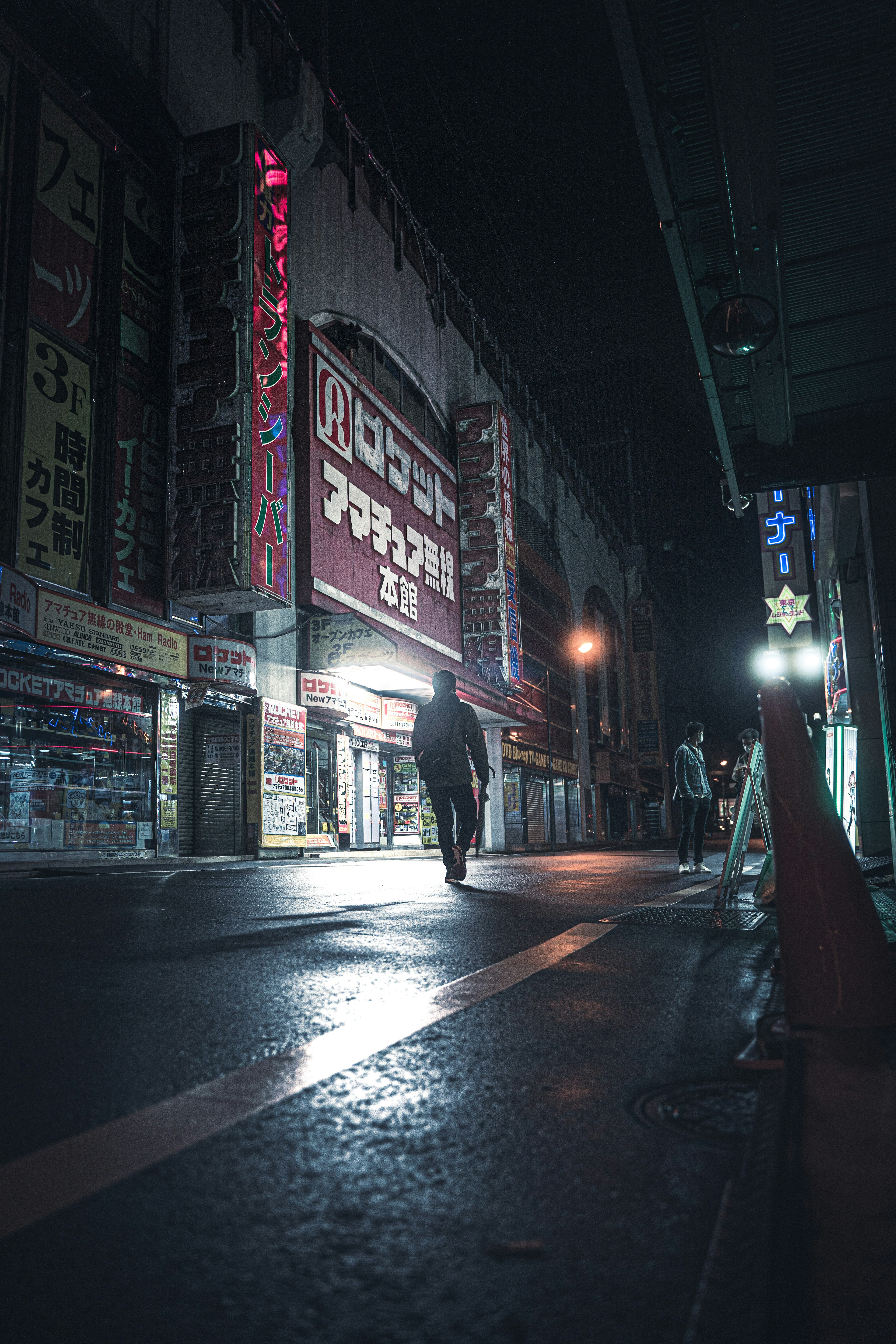 Silhouette of a person walking on a dark street with neon signs