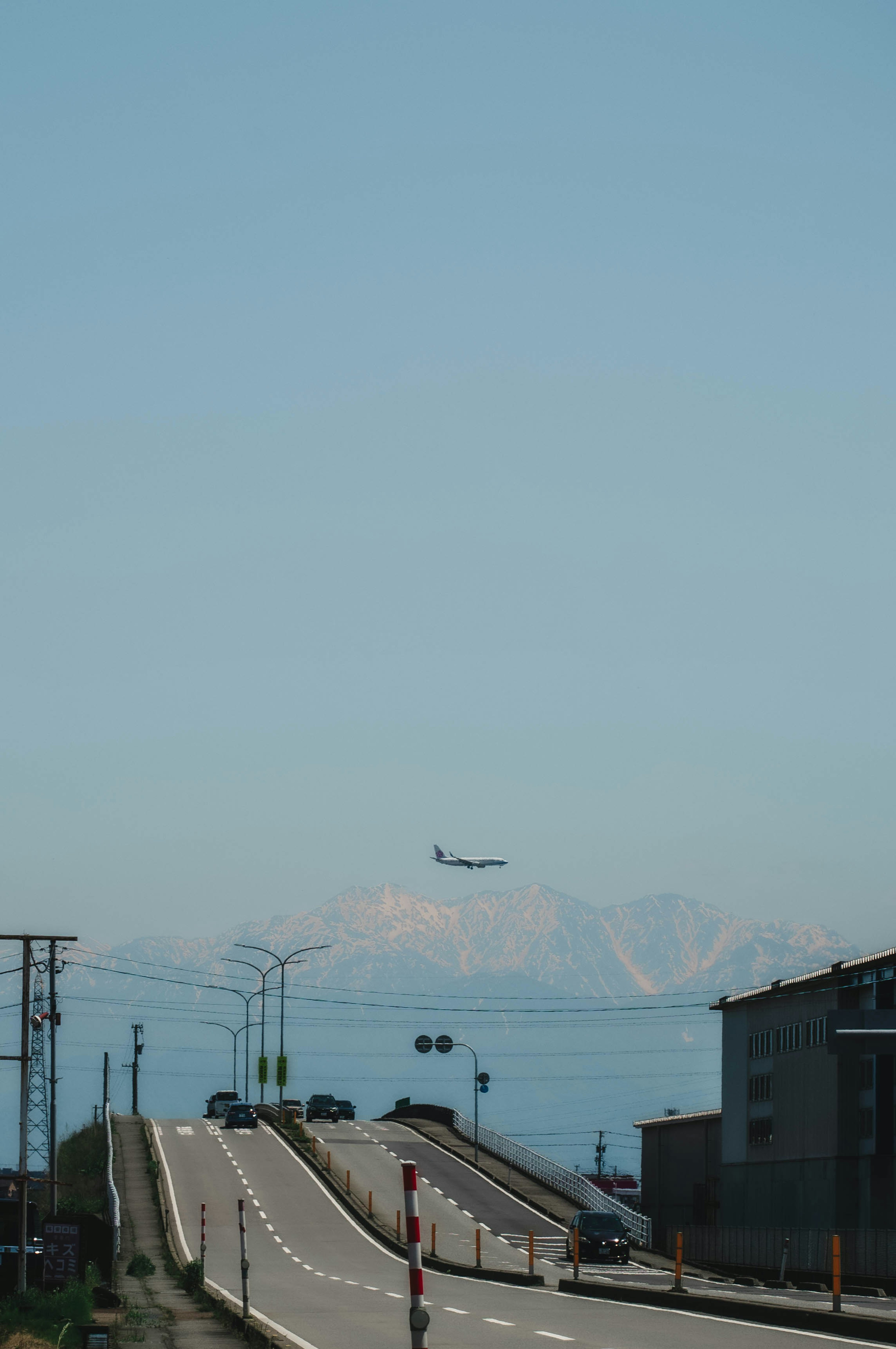 青空の下に広がる道路と山々の背景に着陸する飛行機