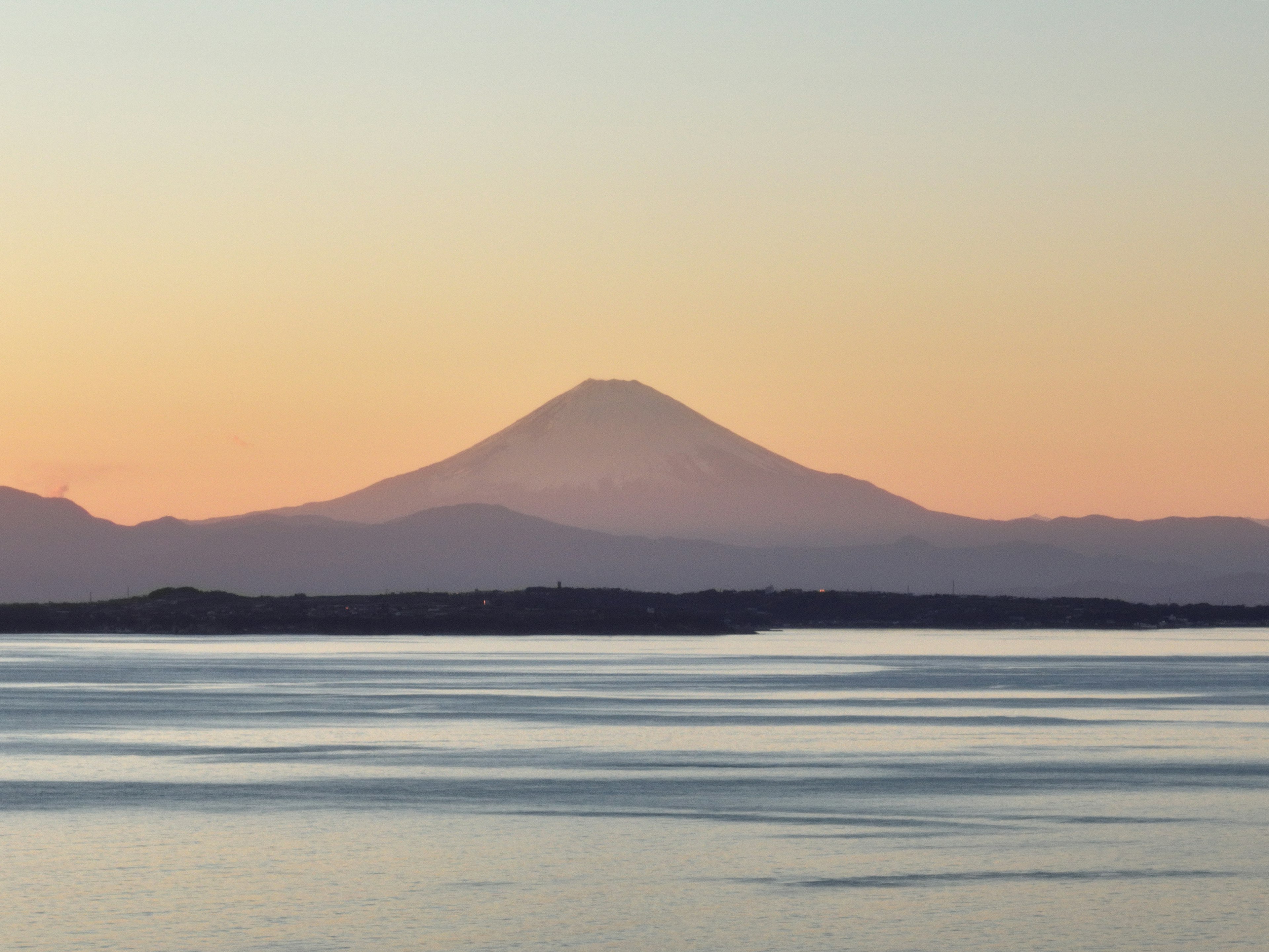 Silhouette de montaña contra un hermoso atardecer sobre agua tranquila