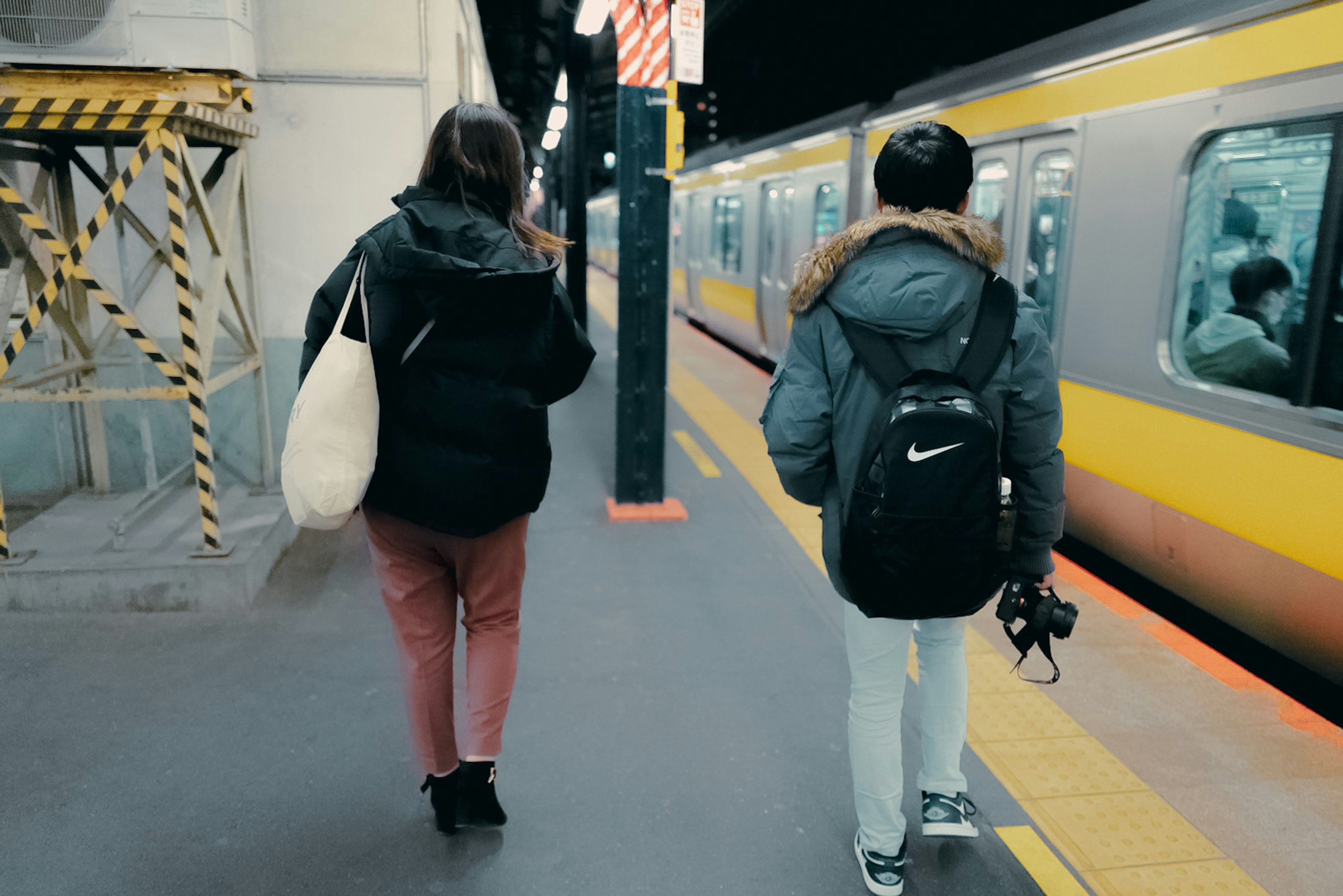 夜の駅で電車を待つ二人の若者