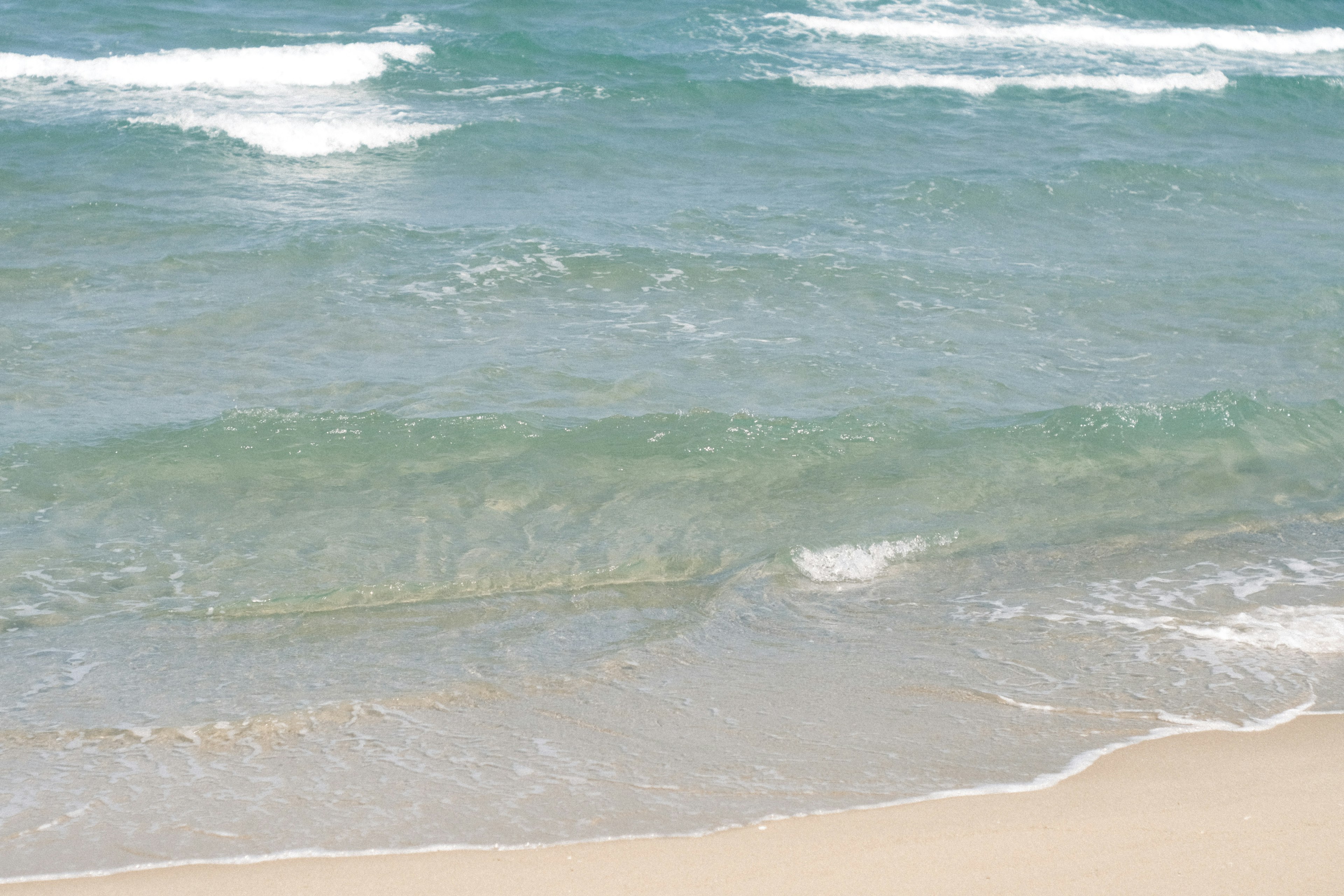 Onde calme che si infrangono su una spiaggia con acqua chiara