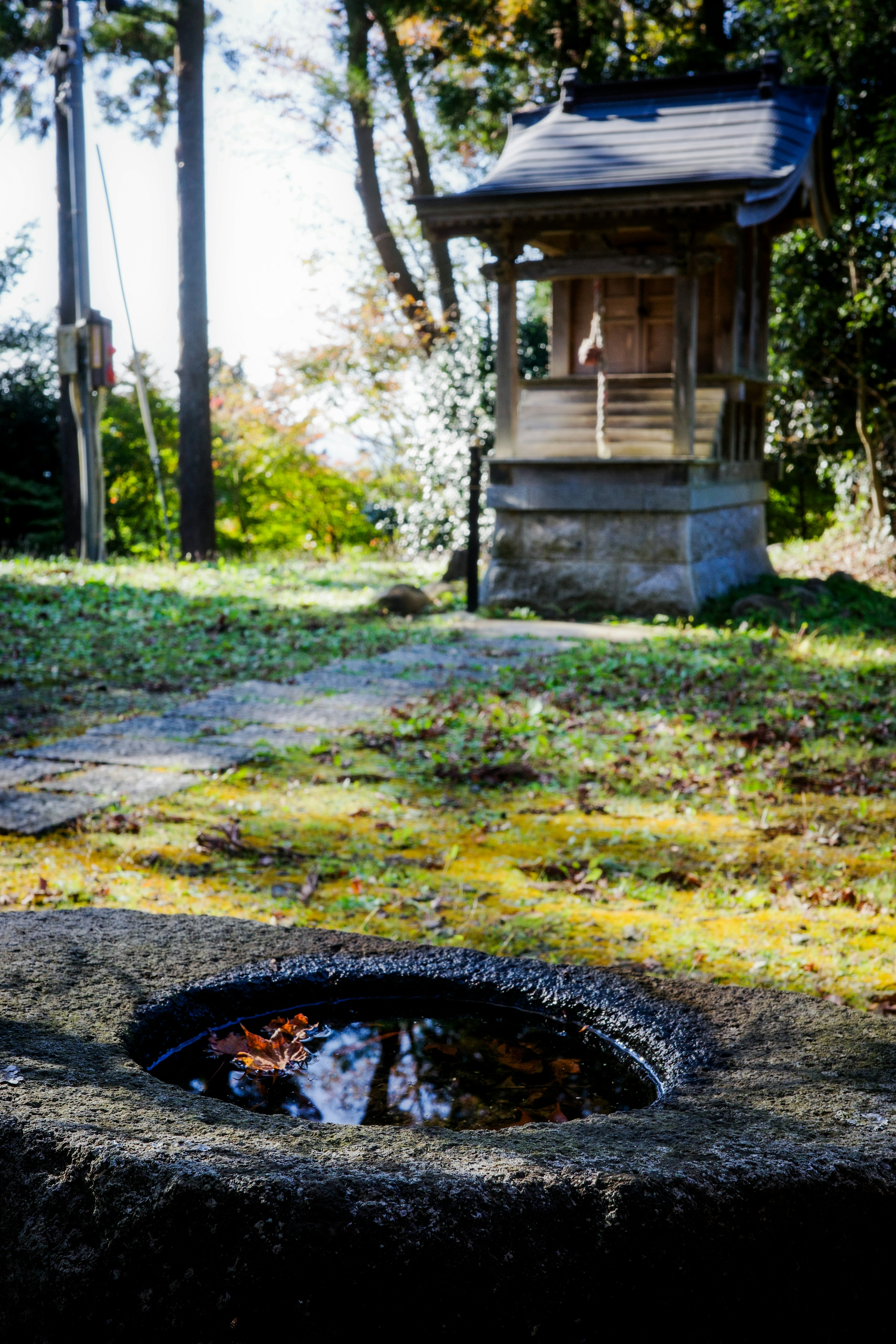 Eine ruhige Szene mit einem alten Brunnen und einem kleinen Schrein