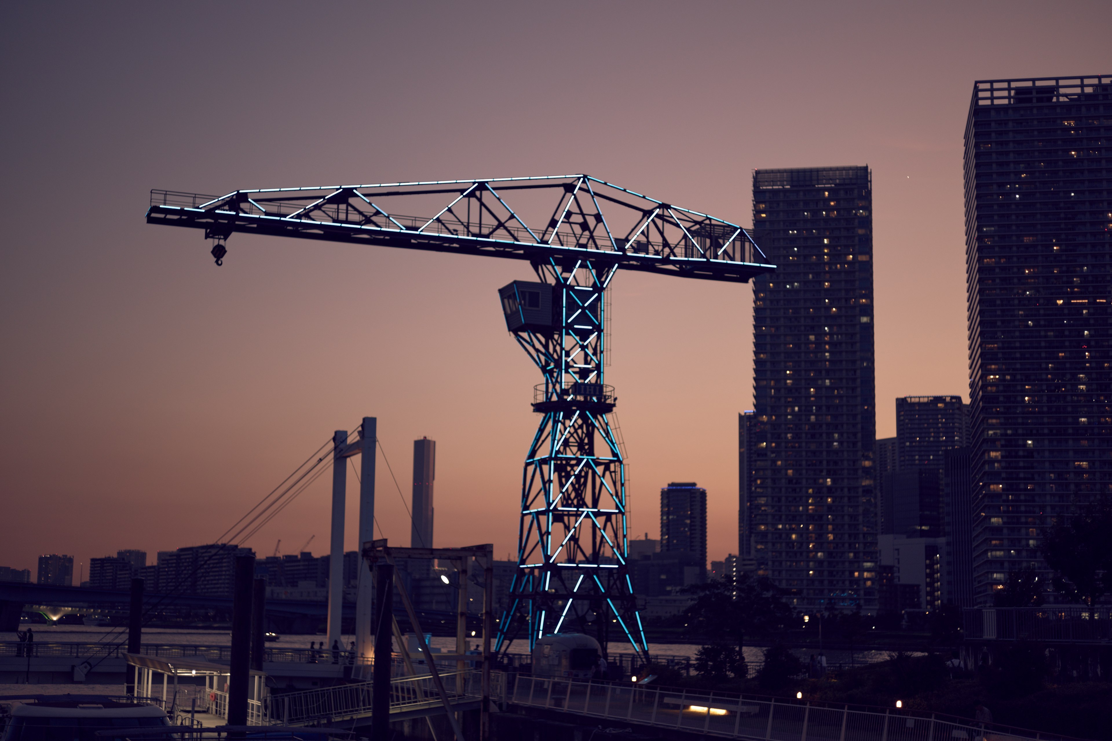 White and blue crane towering against a twilight skyline with skyscrapers