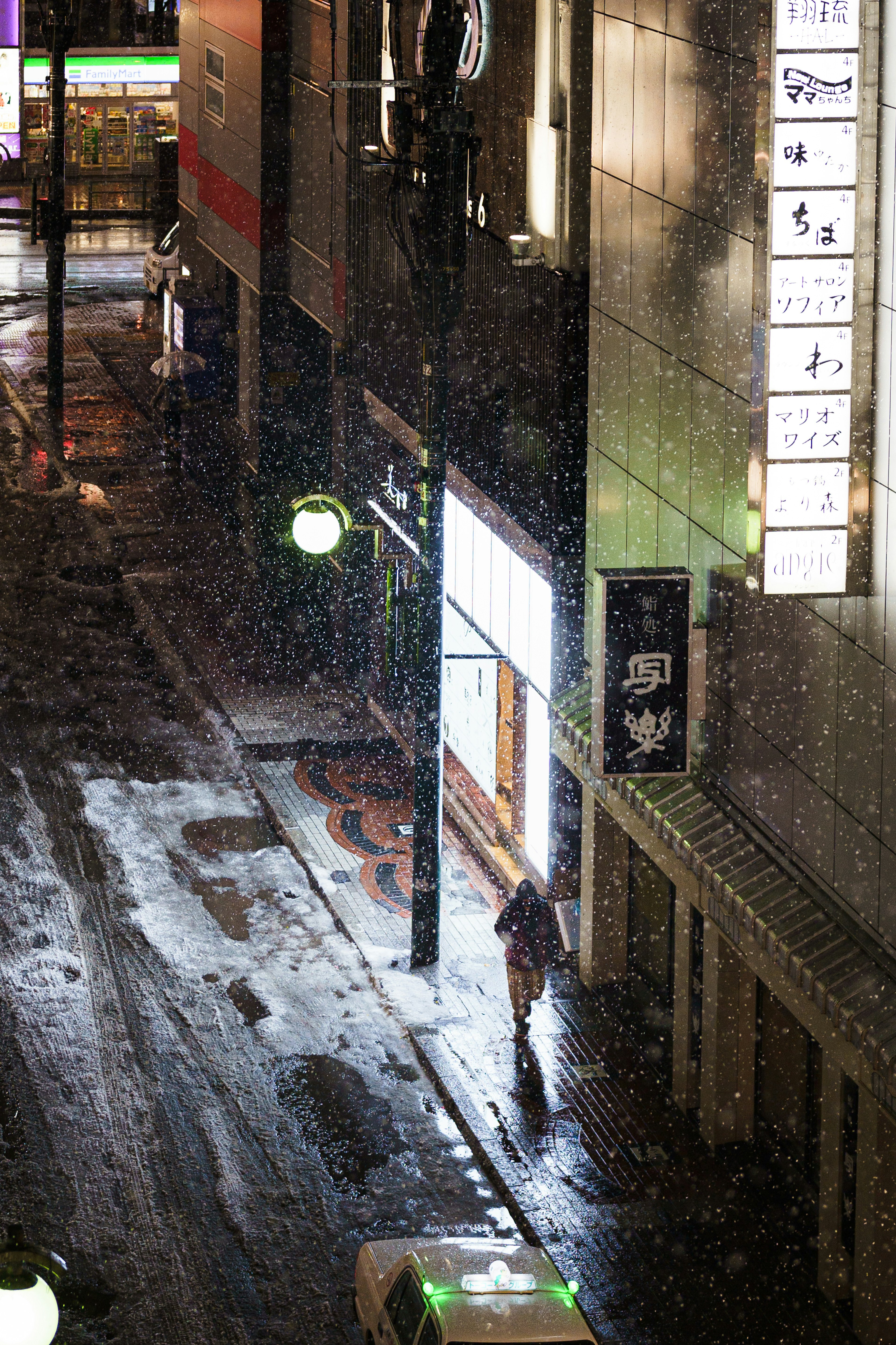 A person walking in the rain on a city street at night