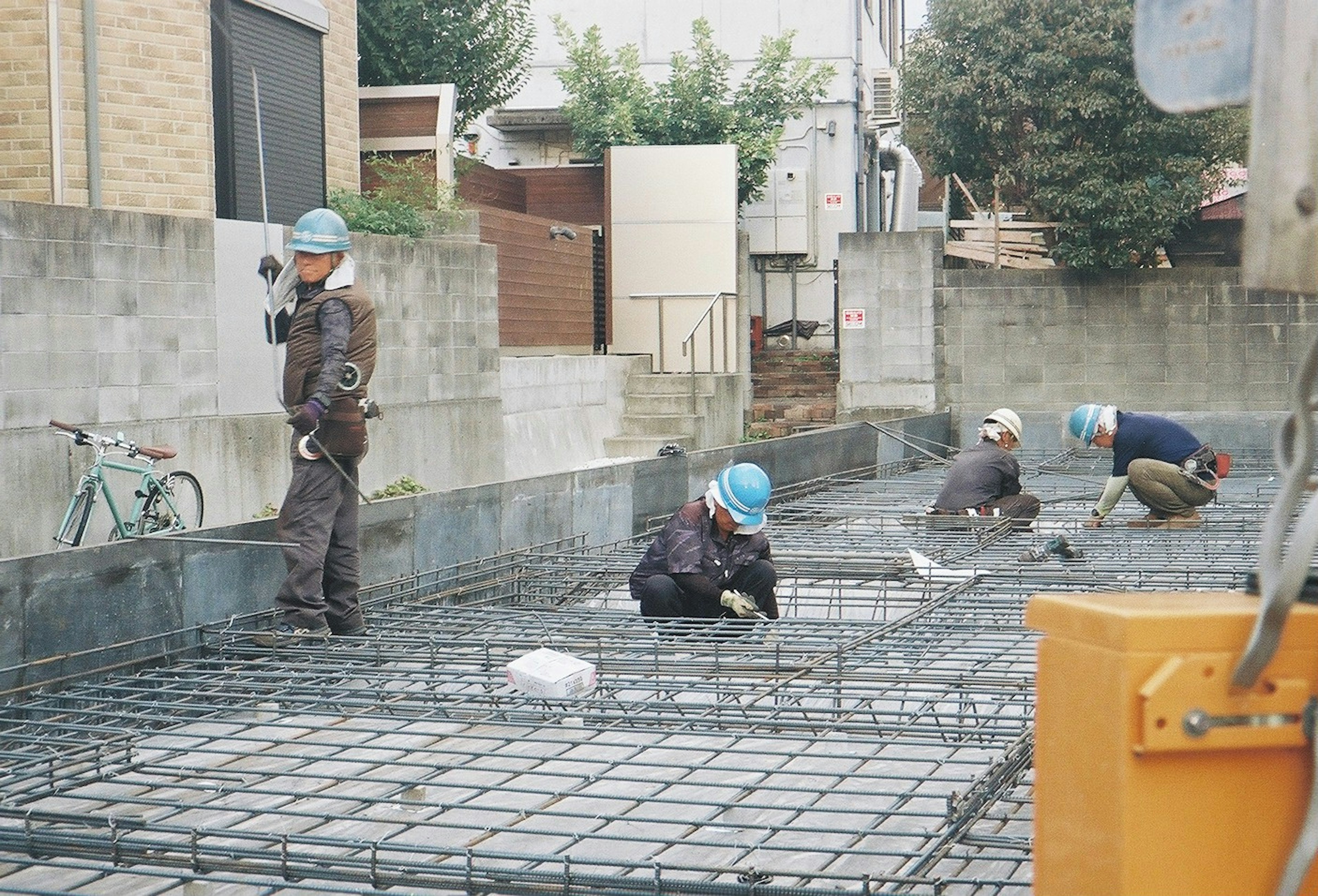 建設現場で作業する作業員たちが見える写真 彼らは鉄筋の上で働いている