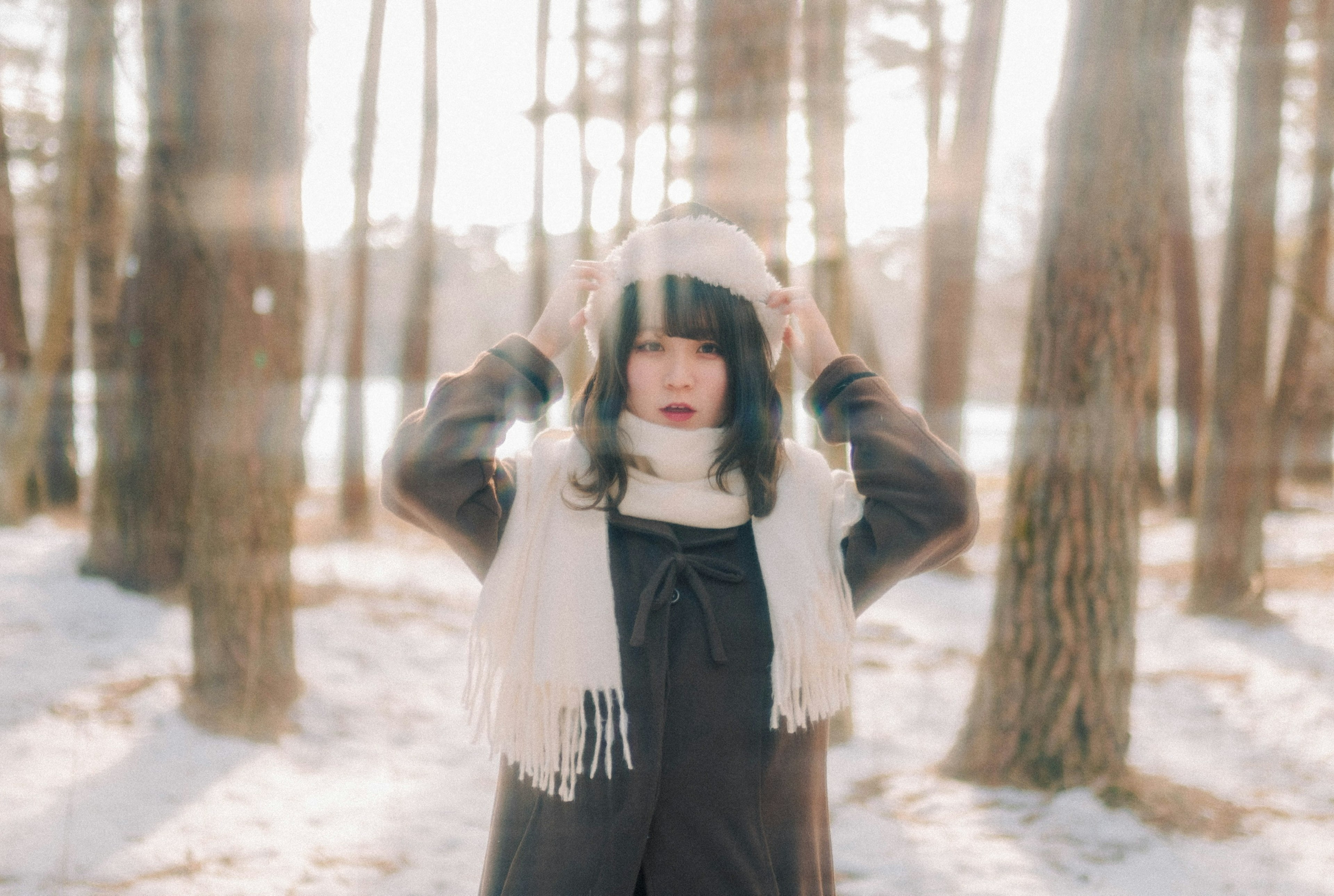 Frau in einem Winterwald mit einem Schal, der ihre Ohren bedeckt