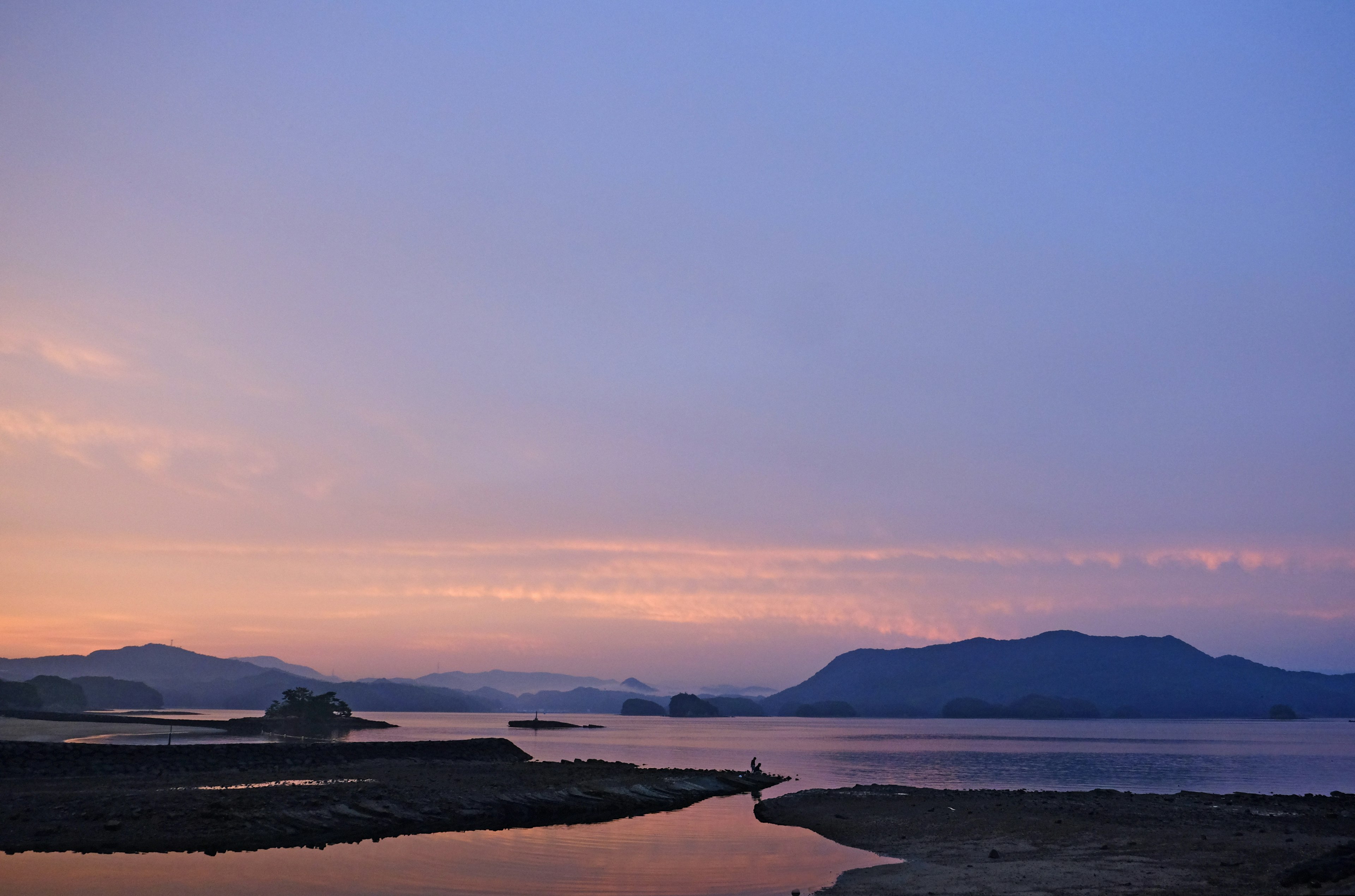 Paesaggio di tramonto calmo con cielo blu e viola superficie d'acqua tranquilla e montagne