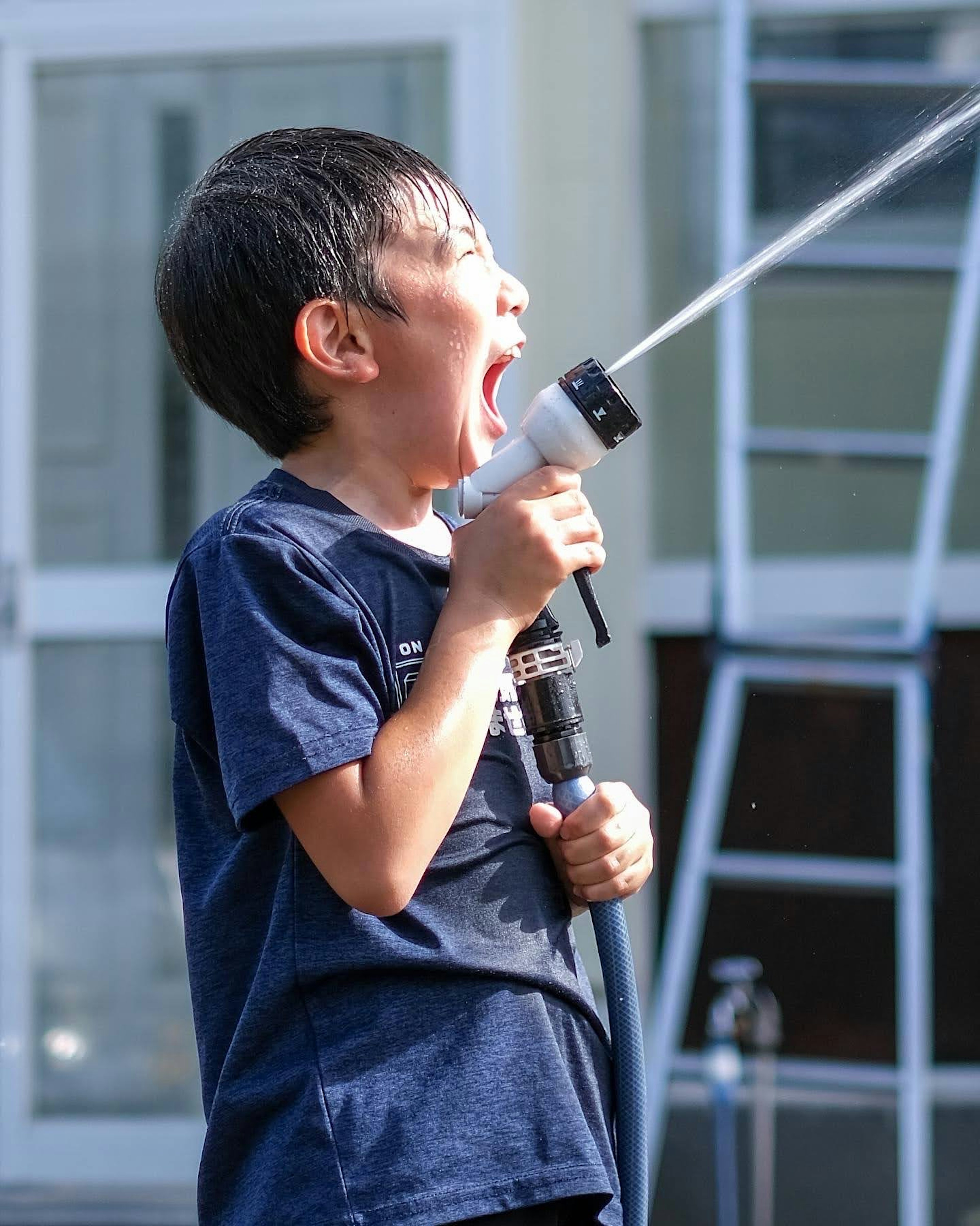 Boy enjoying water spray from a hose