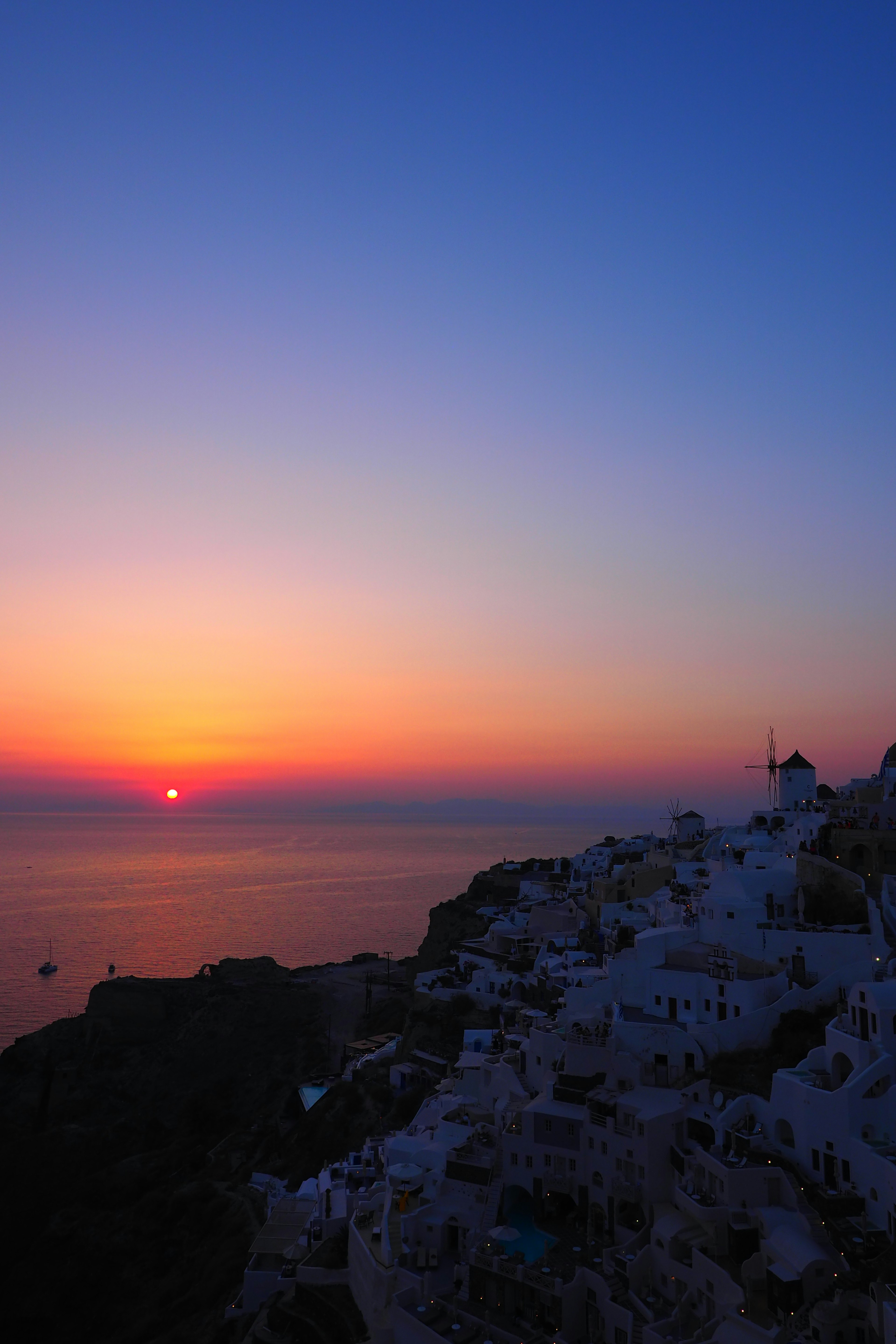 Pemandangan matahari terbenam yang indah di Santorini bangunan putih di tepi tebing