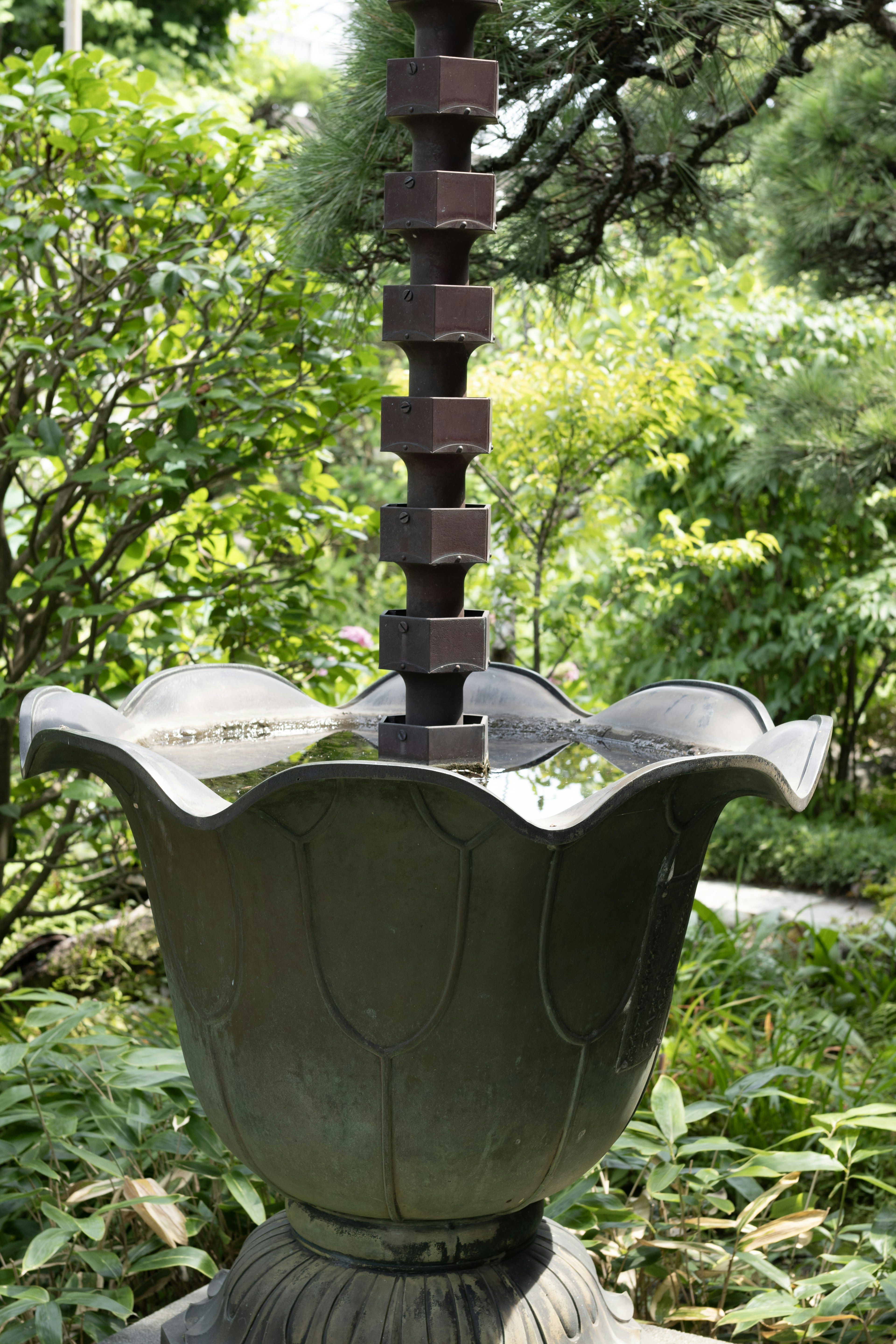 Bañera decorativa de jardín con agua fluyendo y vegetación exuberante