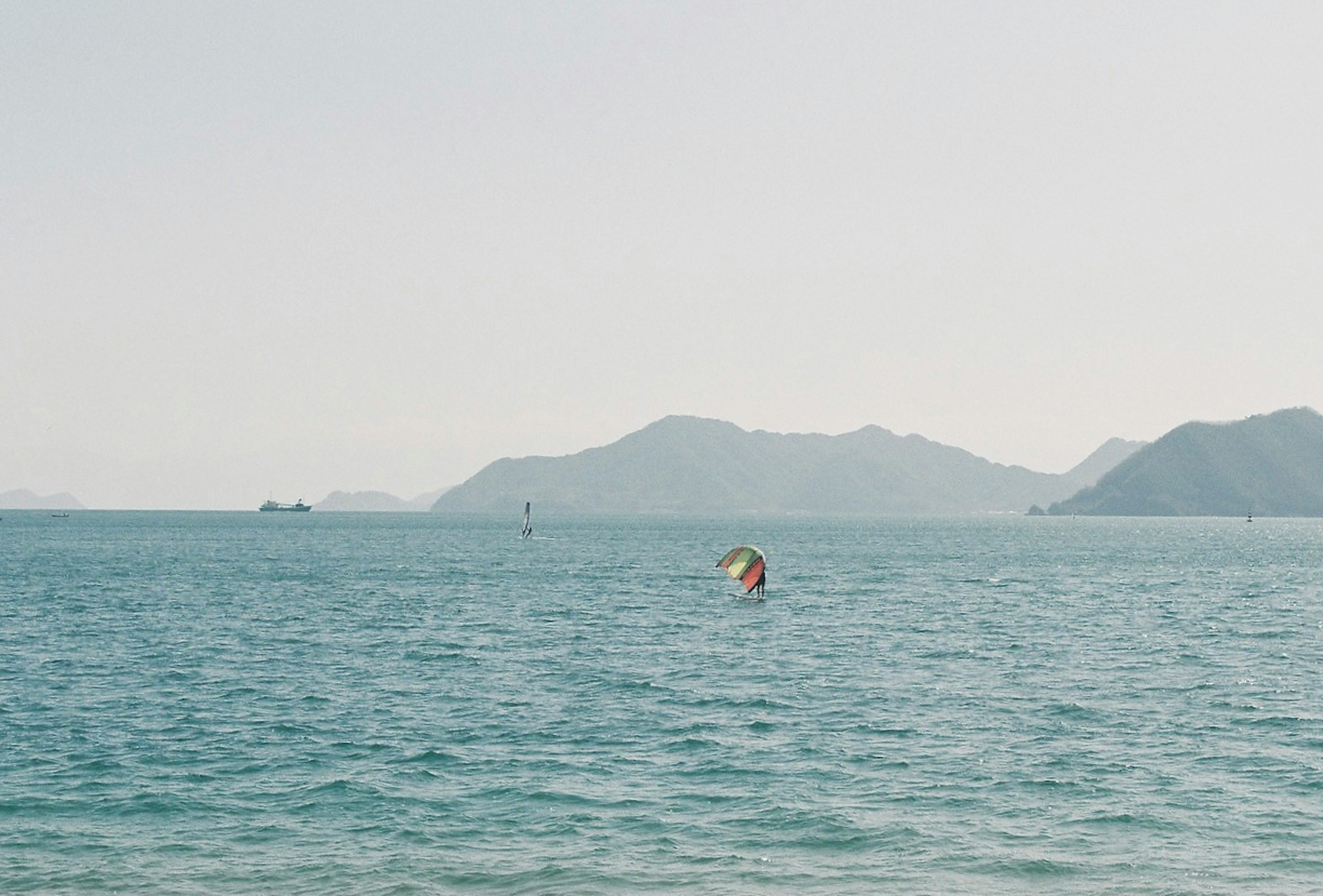 Eine malerische Ansicht des Meeres mit Bergen im Hintergrund und einem Kitesurfer