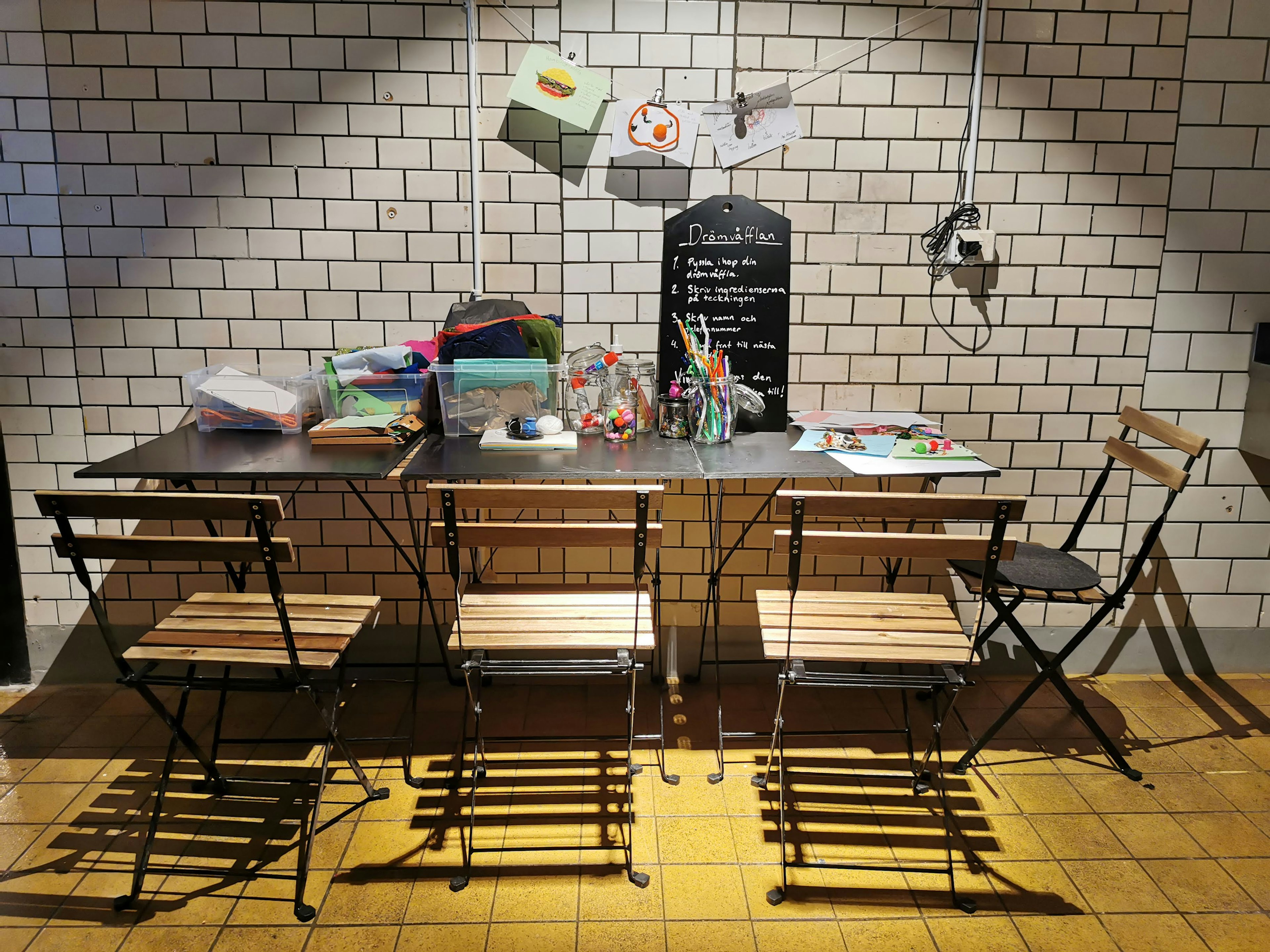 A cafe corner with wooden chairs and a table featuring colorful stationery items