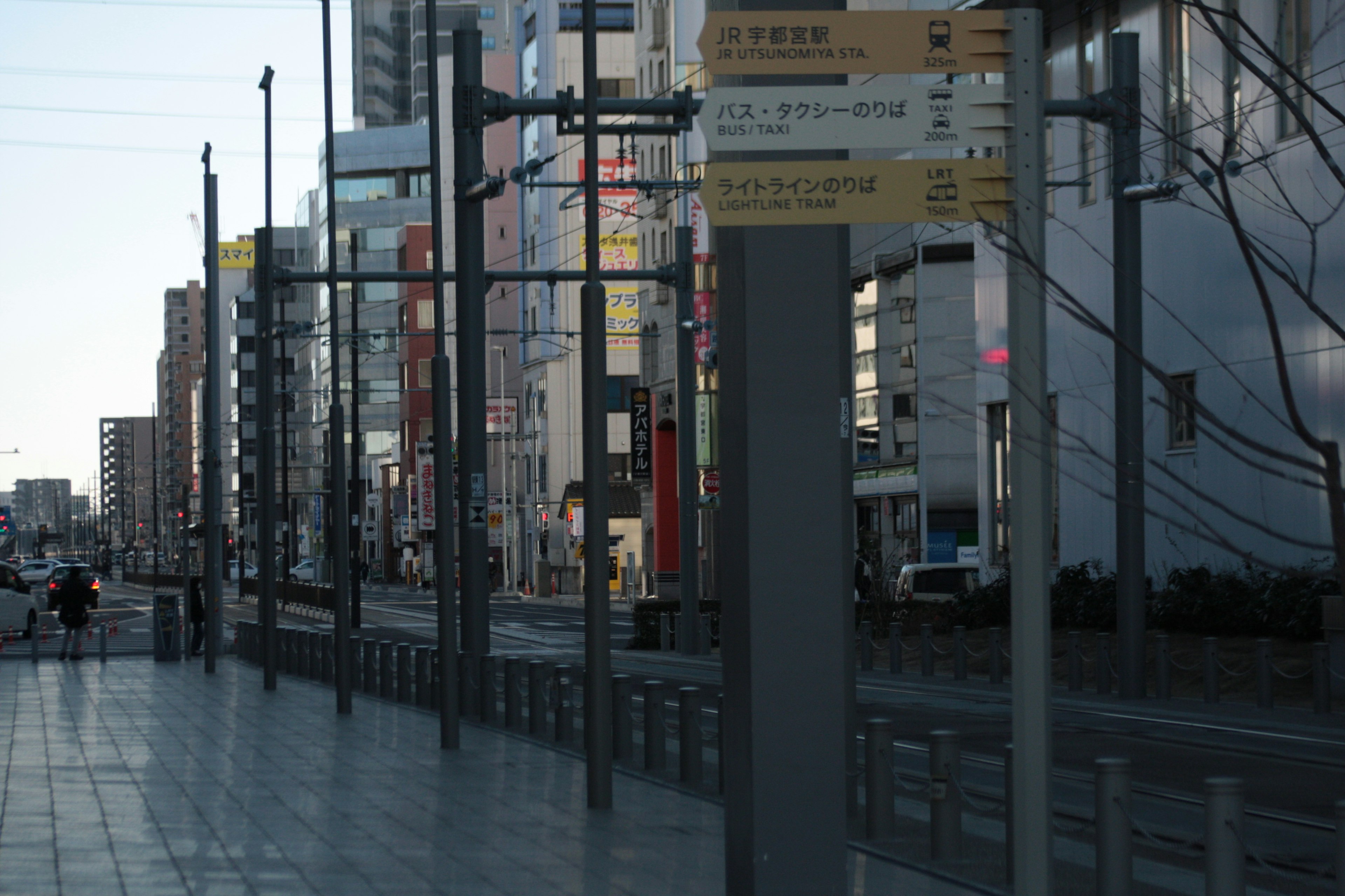 都市の通りの風景に立つバス停と看板