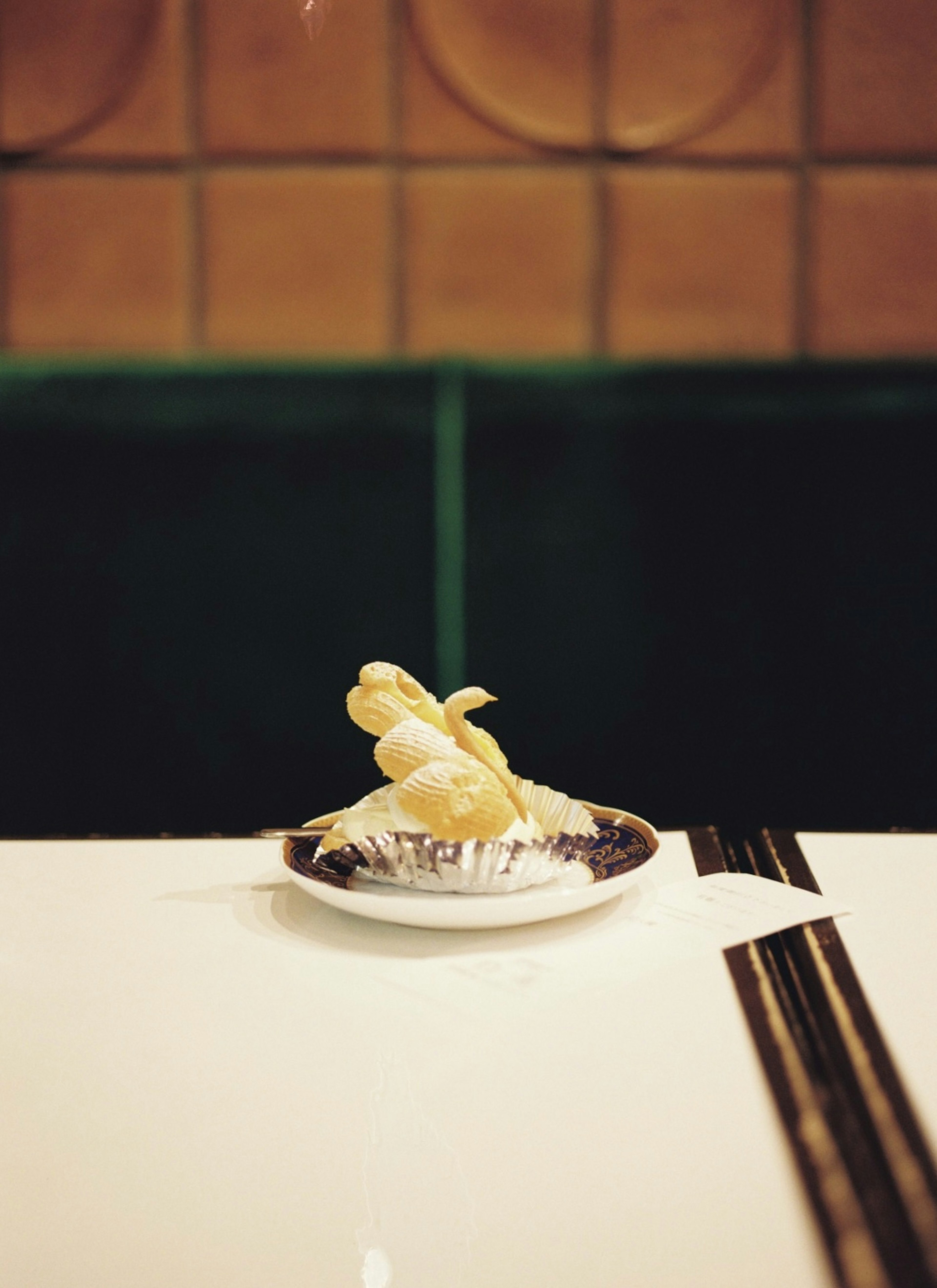 Un dessert blanc sur une petite assiette posé sur une table avec un fond vert