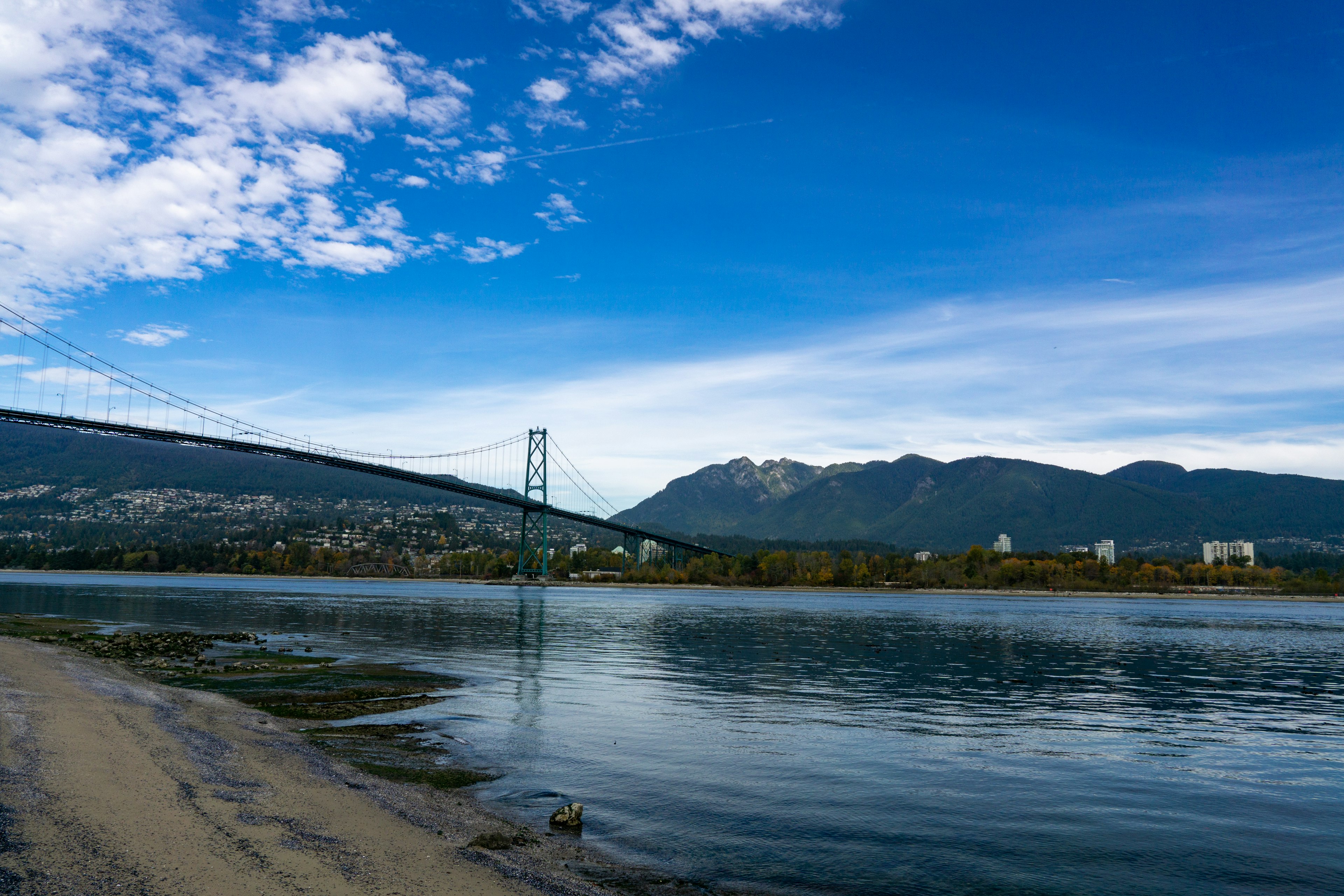 Scenic view of a river with a bridge under a blue sky and clouds