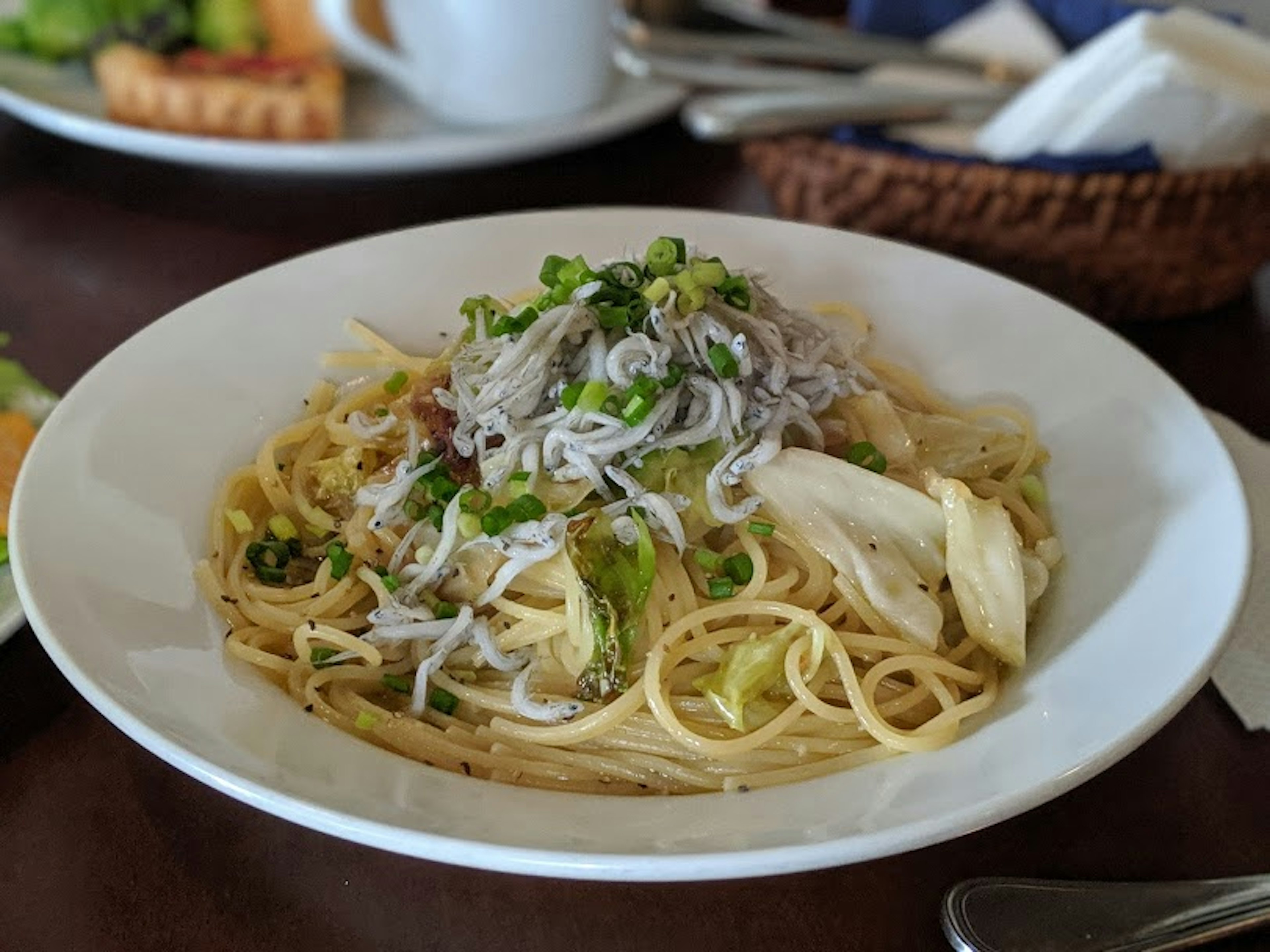 Un piatto di spaghetti guarnito con cavolo e pesciolini