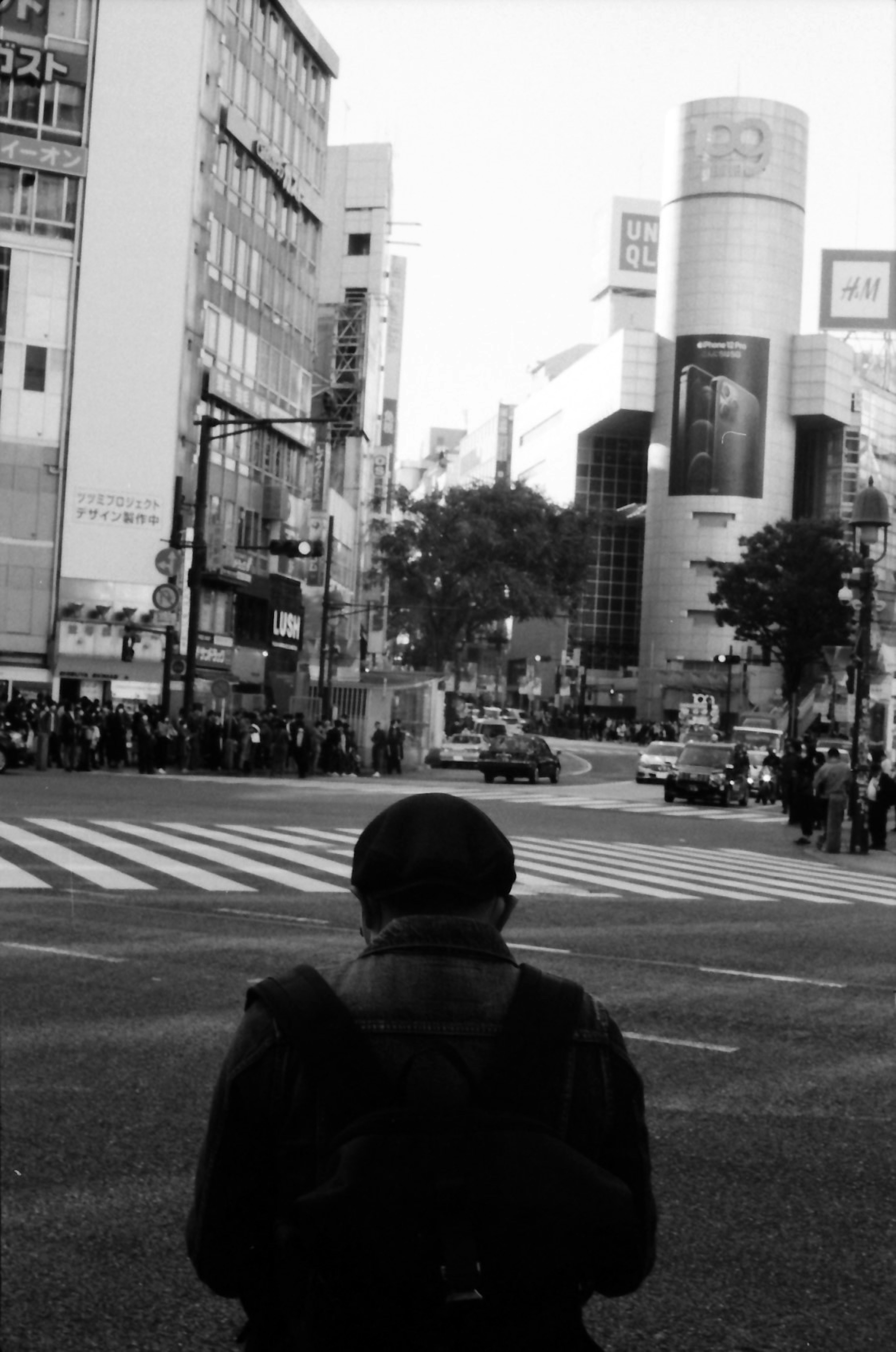 Person steht mit dem Rücken zur Kamera am Shibuya-Kreuzung mit modernen Gebäuden