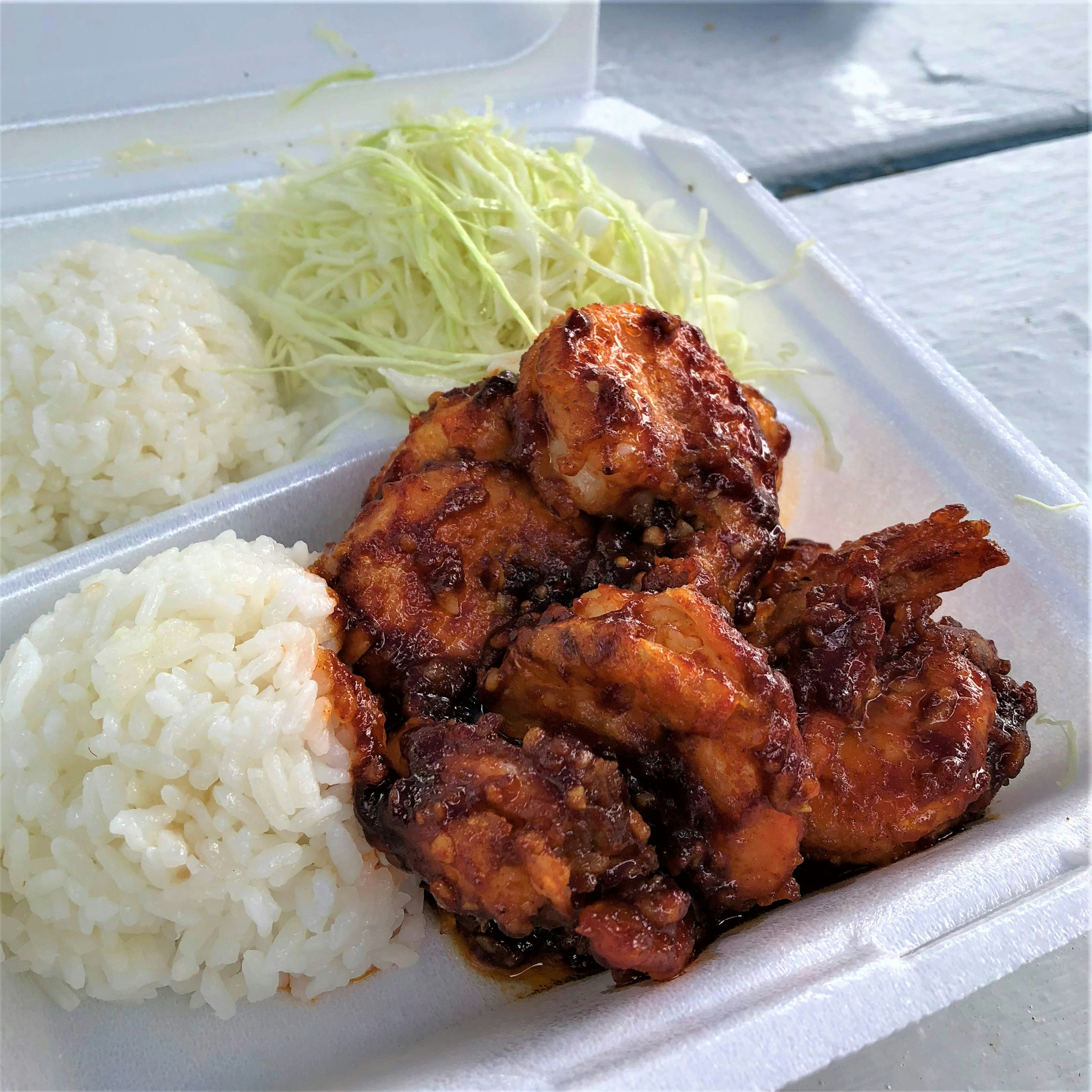 Grilled shrimp dish served with white rice and shredded cabbage