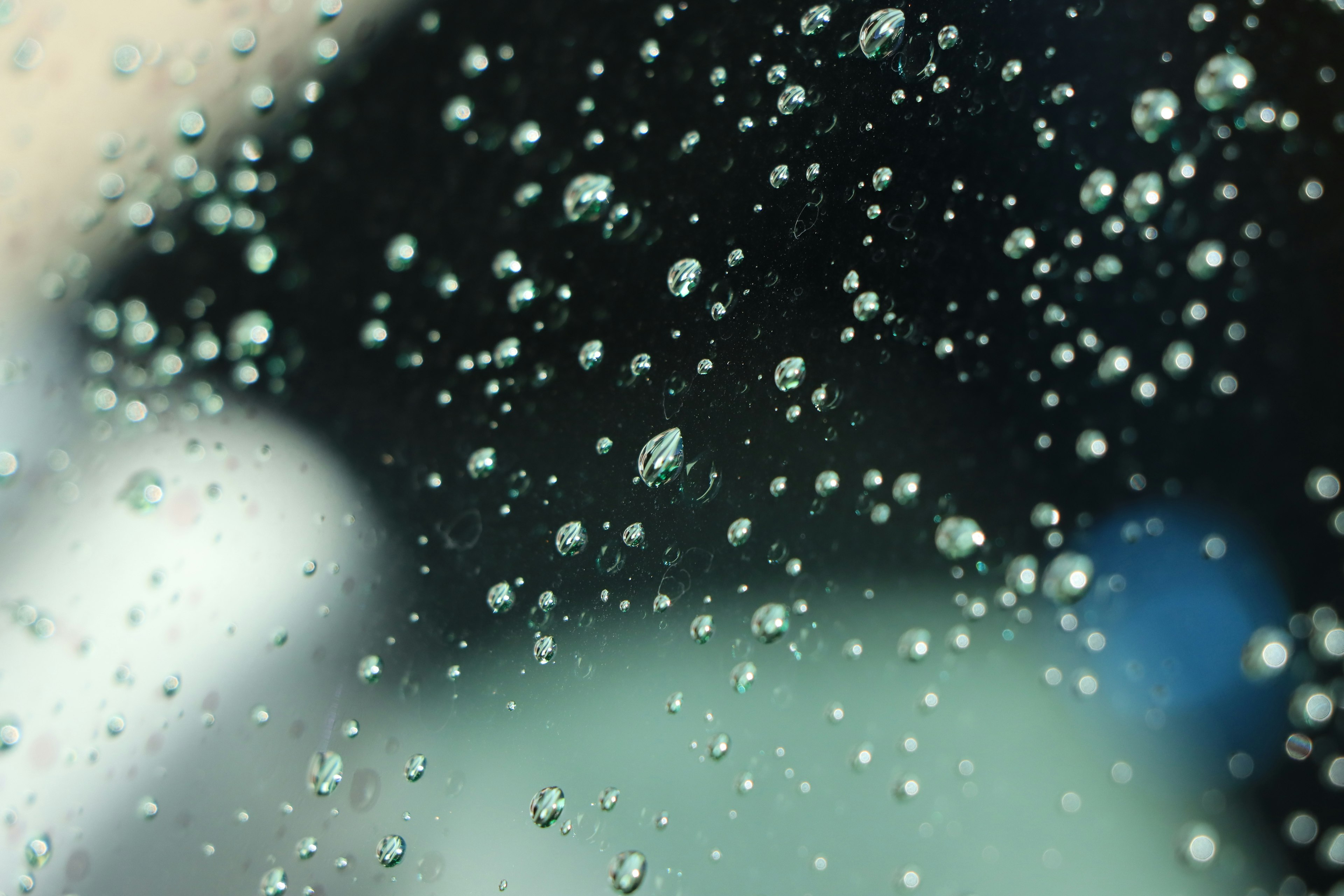 Close-up of water droplets on a window with a blurred background