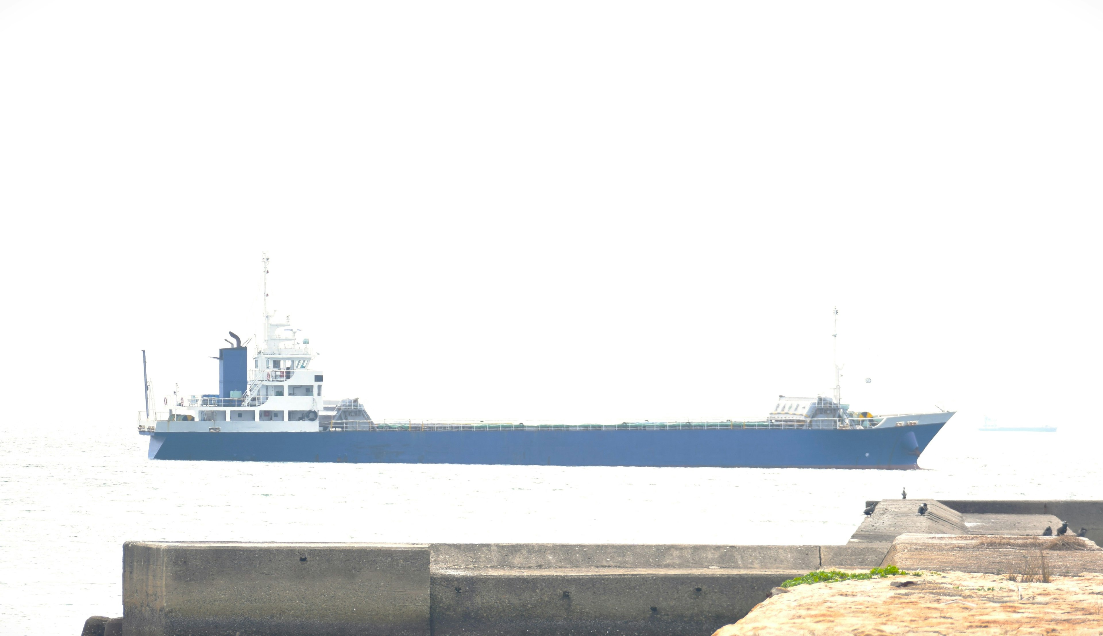 A blue cargo ship docked at a port