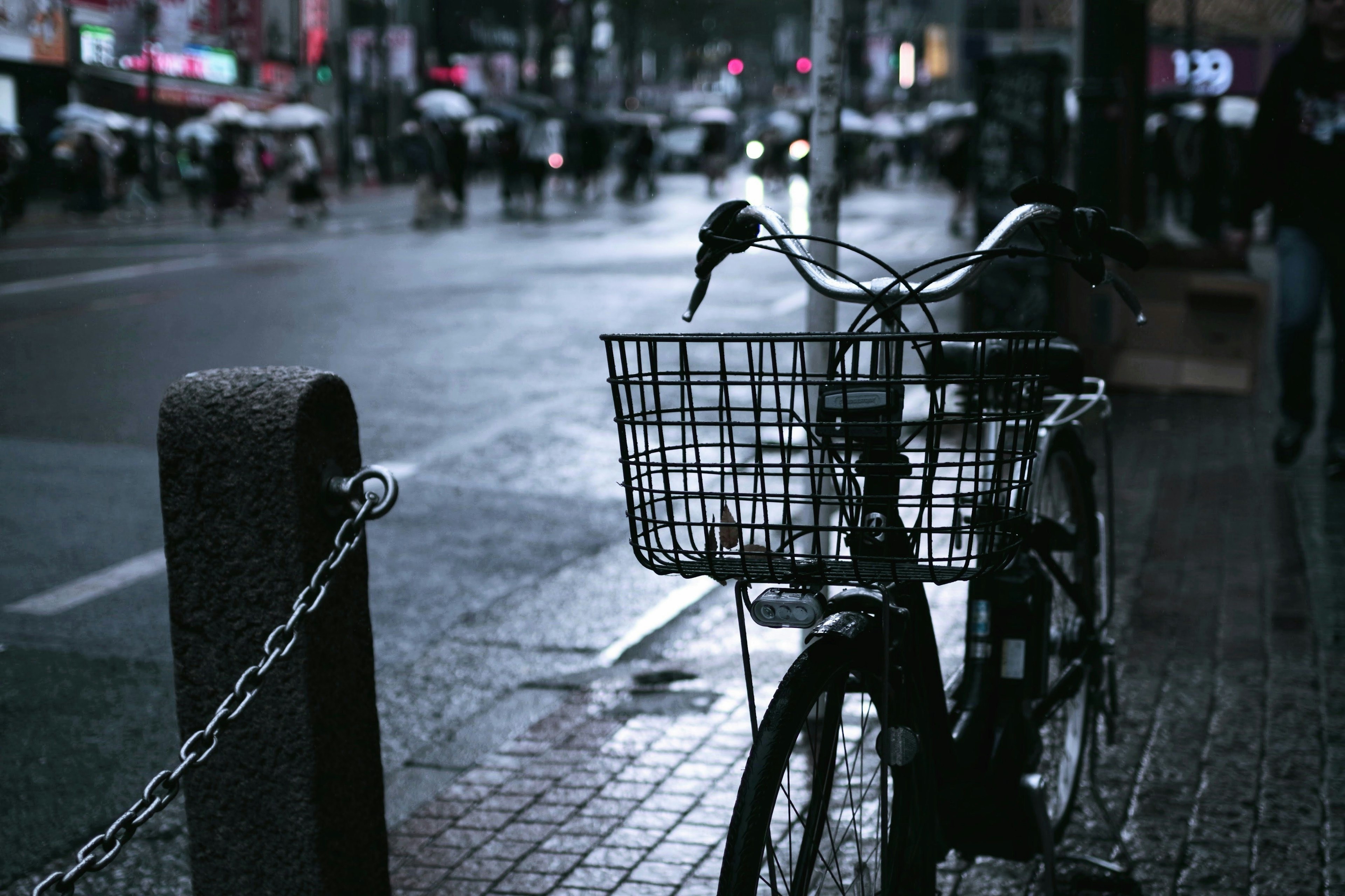 A bicycle parked on a wet street with a dark atmosphere and reflections